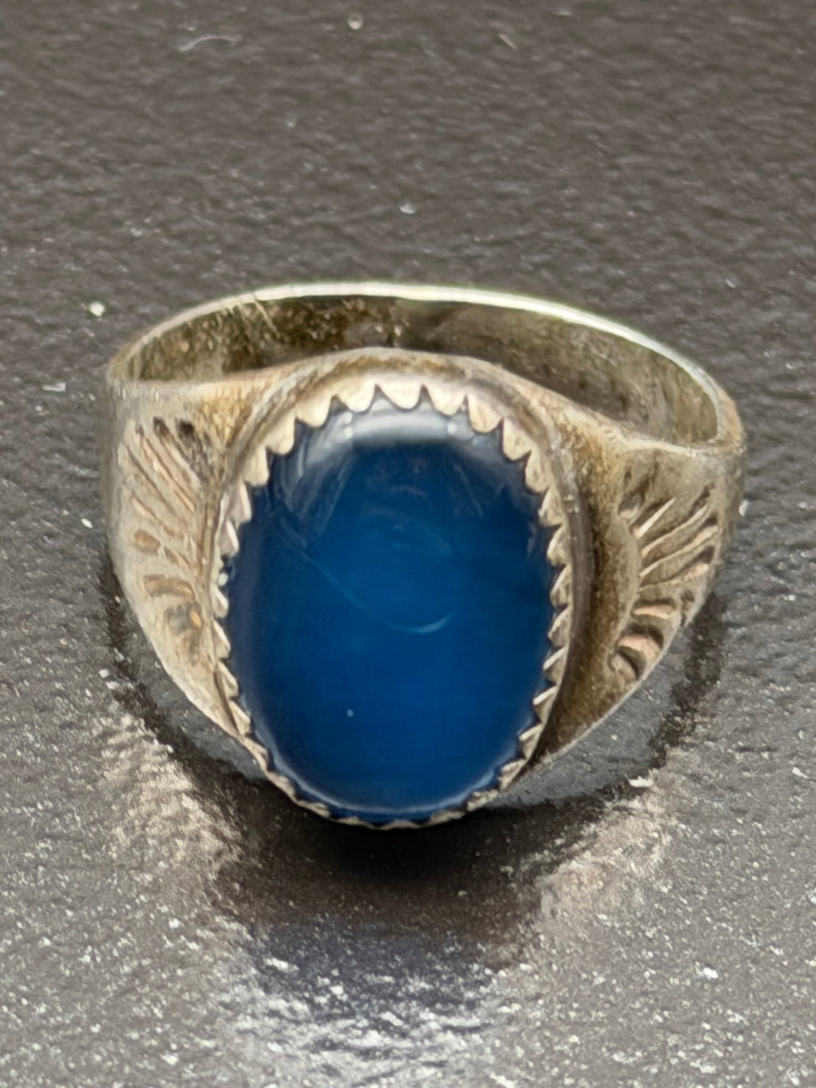 5g-Vintage Sterling Silver Blue Cabochon Ring Oval Bezel Set Southwestern: Vintage sterling silver ring featuring a polished oval deep blue cabochon gemstone (possibly blue chalcedony, dyed agate, or onyx) in a classic serrated bezel setting. The shoulders are hand-stamped w