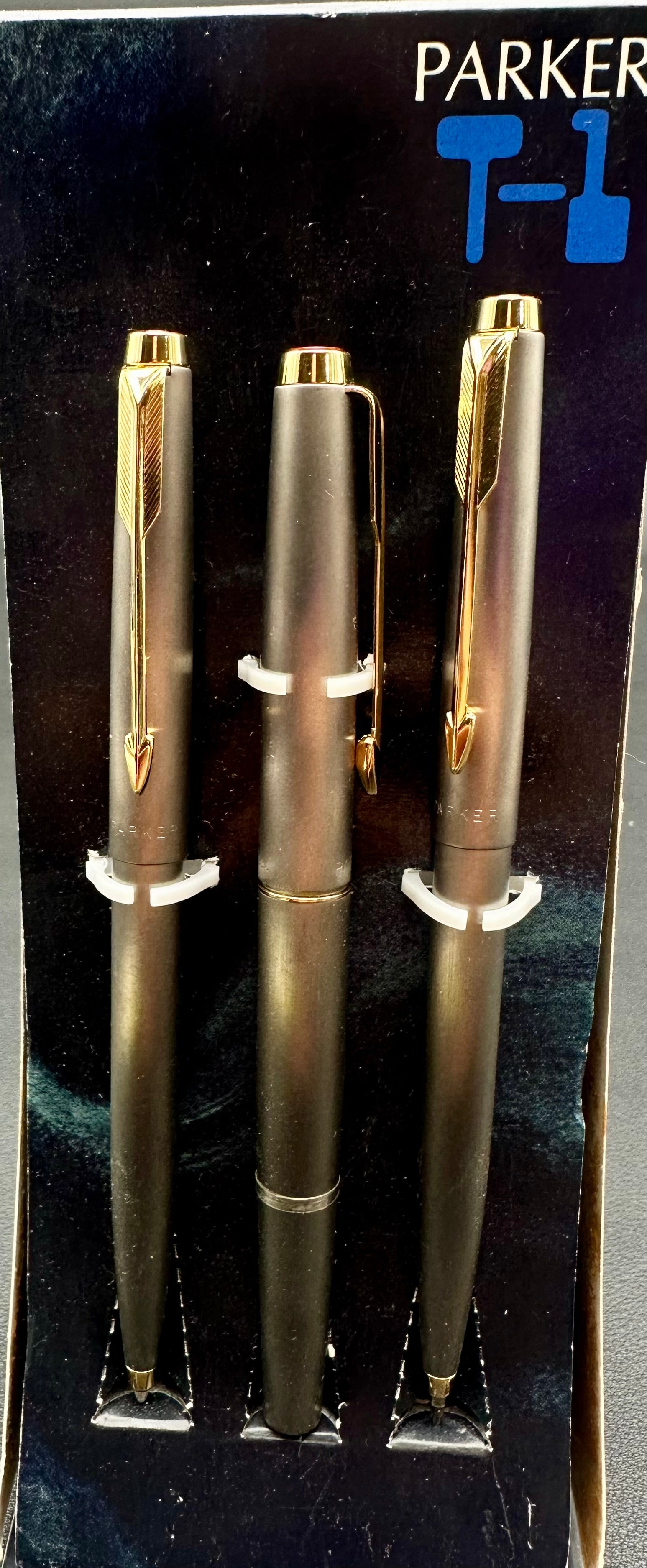 Vintage Parker T1 Titanium Fountain Pen Ballpoint Pencil 3-Piece Set Box: Vintage Parker T1 three-piece writing set including a fountain pen, ballpoint pen, and mechanical pencil in a brushed titanium finish with gold-tone arrow clips. Includes the original Parker display b
