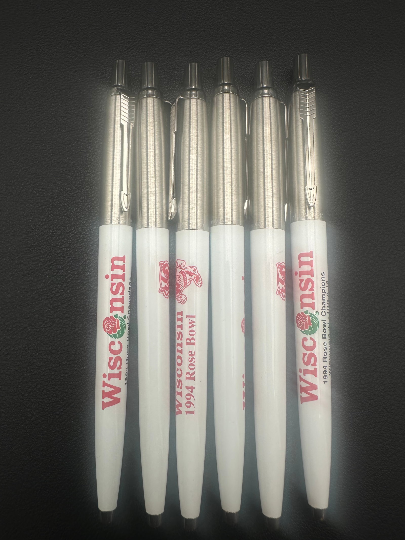 Lot of 6 Parker Jotter Wisconsin 1994 Rose Bowl Champions Ballpoint Pens NOS: Set of six New Old Stock (NOS) Parker Jotter ballpoint pens featuring Wisconsin Badgers “1994 Rose Bowl Champions” advertising graphics. White plastic barrels with brushed stainless steel caps