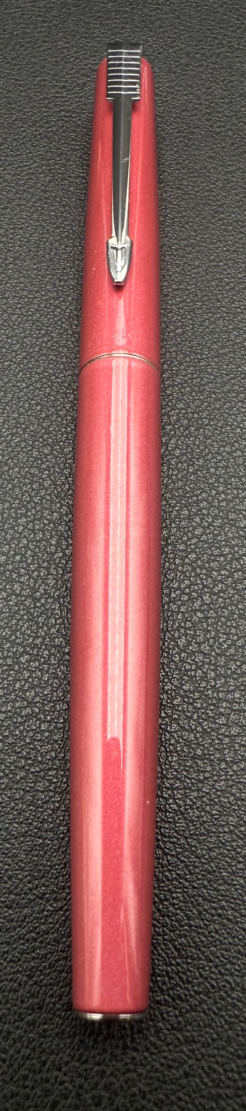 Vintage Parker Pink Fountain Pen Stainless Steel Nib: Vintage Parker fountain pen with a metallic pink finish, chrome arrow clip, and stainless steel Parker nib. Features a slim, elegant design and includes the original cap. Shows light signs of normal u