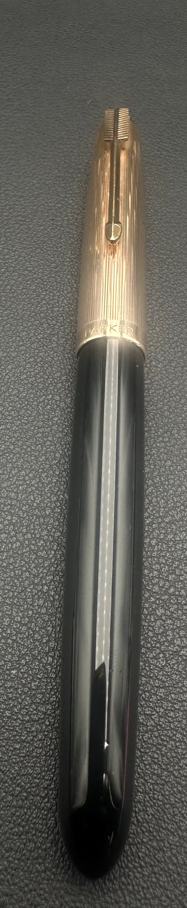 Parker 51 Fountain Pen Black 1/10 12K Gold Filled Cap USA: Vintage Parker 51 fountain pen featuring a black Lucite barrel with a lined 1/10 12K gold-filled cap and the classic Parker arrow clip. The cap is marked “1/10 12K Gold Filled,” indicating a q