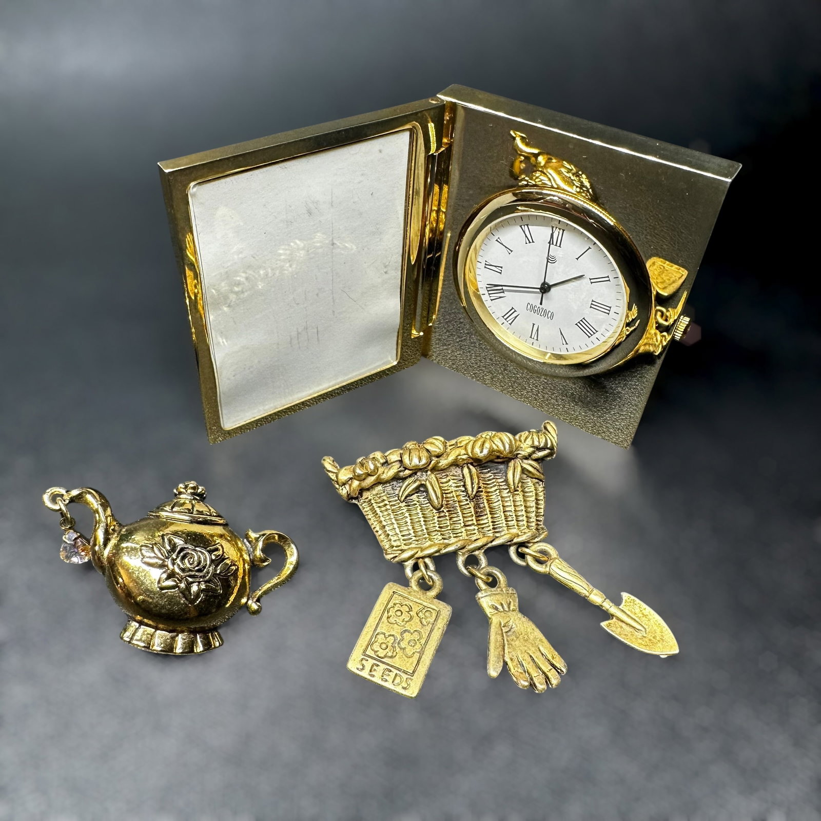 Vintage Gold Tone Clock/Frame, Brooch & Teapot Pin Lot: Vintage Gold Tone Clock/Frame, Brooch & Teapot Pin Lot:Brand/Model: COGOZOCO desk clock. No hallmark. Unidentified artisan/shop.Manufacturer Location: Not marked.Year Produced: Unknown.Condition: Over
