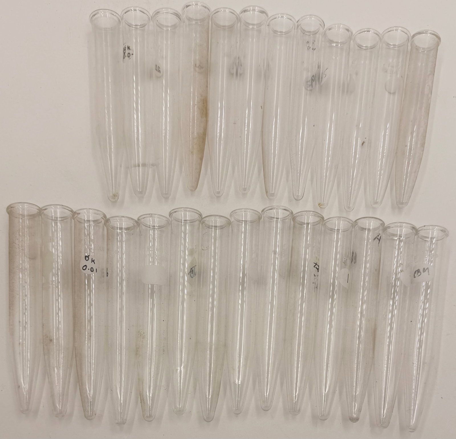 Lot 26 Vintage Glass Test Tubes: This lot includes 26 vintage glass test tubes, believed to be manufactured by Pyrex, Kimax, or a similar laboratory glassware maker. Made from durable borosilicate glass, these clear test tubes are