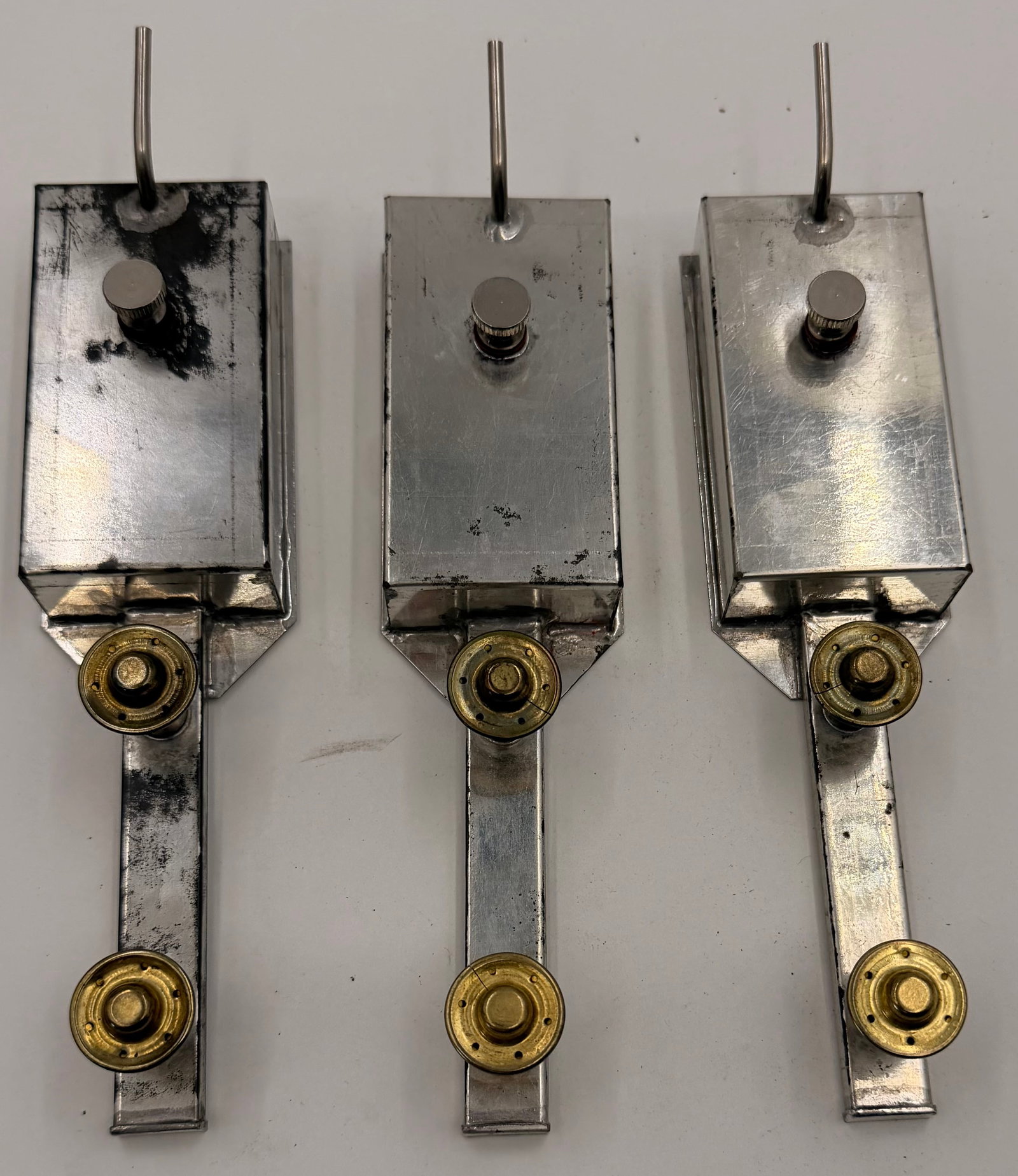 Lot 3 Vintage Industrial Oilers Reservoirs: This lot includes three vintage industrial lubricator or fluid reservoir units of unknown manufacture. Each features a welded sheet-metal reservoir with a knurled fill cap, brass fittings, and an atta