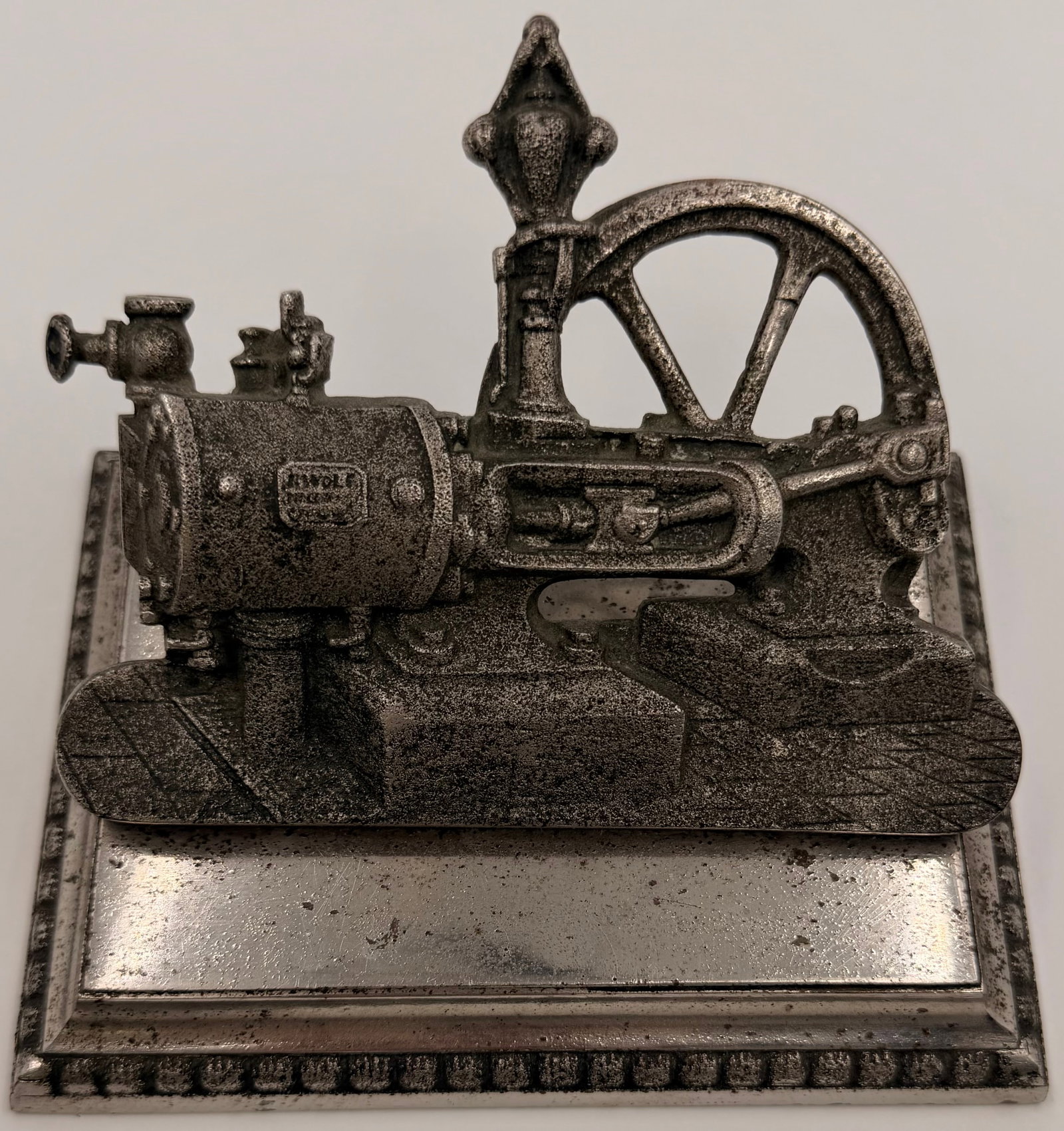 Antique Cast Iron Horizontal Steam Engine Model Display: Antique cast iron miniature horizontal steam engine display model featuring a detailed boiler, cylinder, flywheel, and machined metal base. The engine has a cast-in maker’s cartouche on the boiler