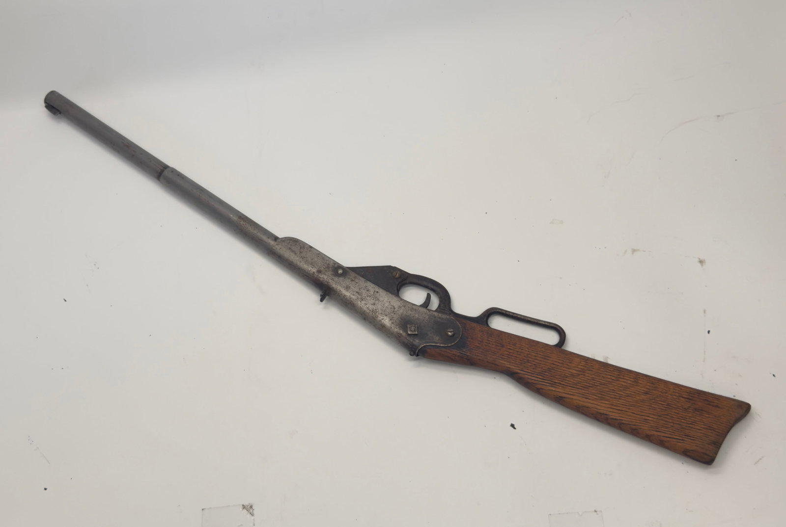 Antique Daisy Lever Action BB Air Rifle c.1910s–1920s: Antique Daisy lever-action BB air rifle featuring an early steel receiver with the classic DAISY target-logo marking, hardwood stock, and tubular barrel. Displays original aged patina, finish wear, an