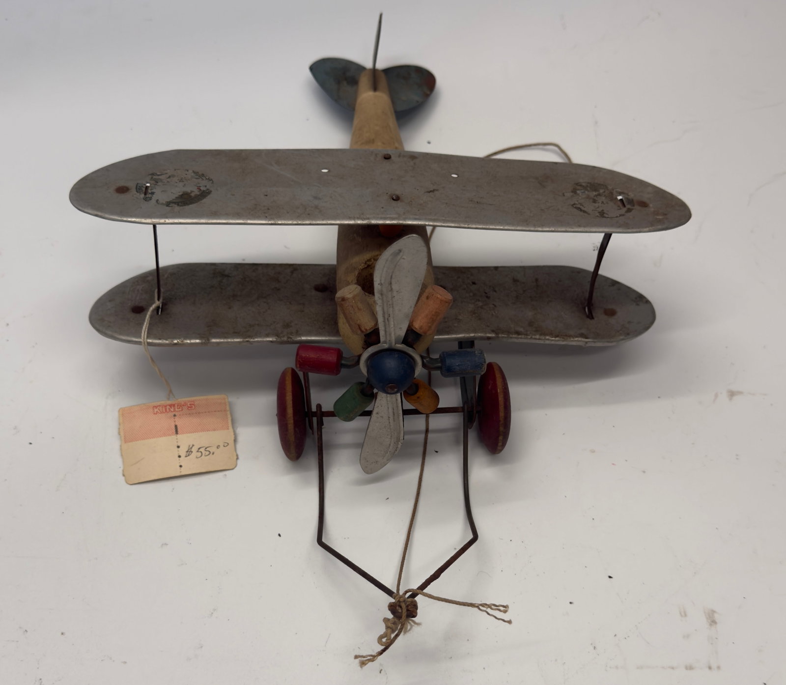 Vintage Wooden & Tin Toy Biplane Pull Toy: Vintage pull-along toy biplane featuring a carved wooden fuselage, pressed tin wings and tail, colorful wooden propeller, and red wooden wheels with wire landing gear. Likely American or European made