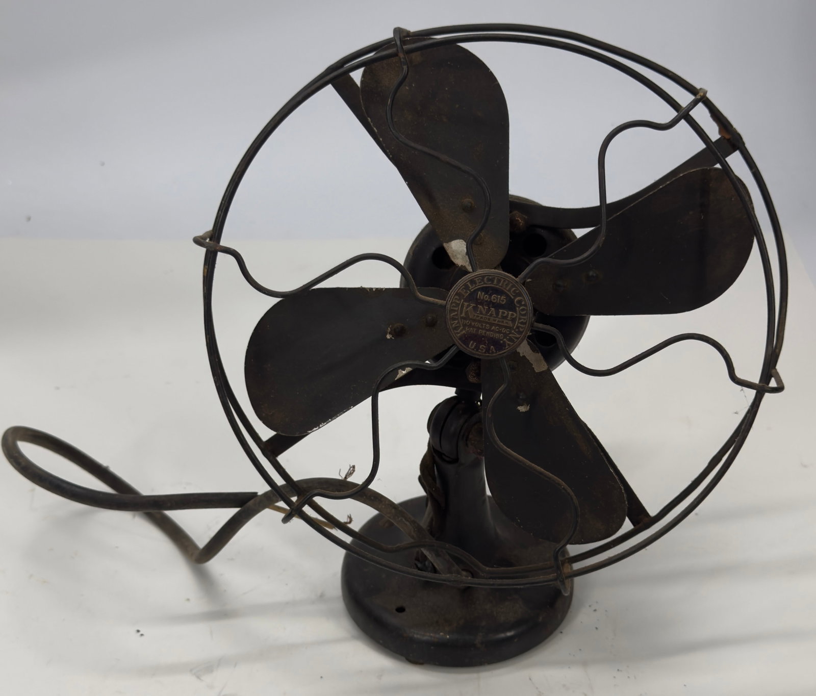 Antique Knapp Electric Co. 4-Blade Desk Fan c.1915–1925: Antique Knapp Electric Company desk fan featuring a four-blade metal fan, wire safety cage, and cast-iron base with an adjustable head. Retains the original Knapp maker’s badge on the front hub and