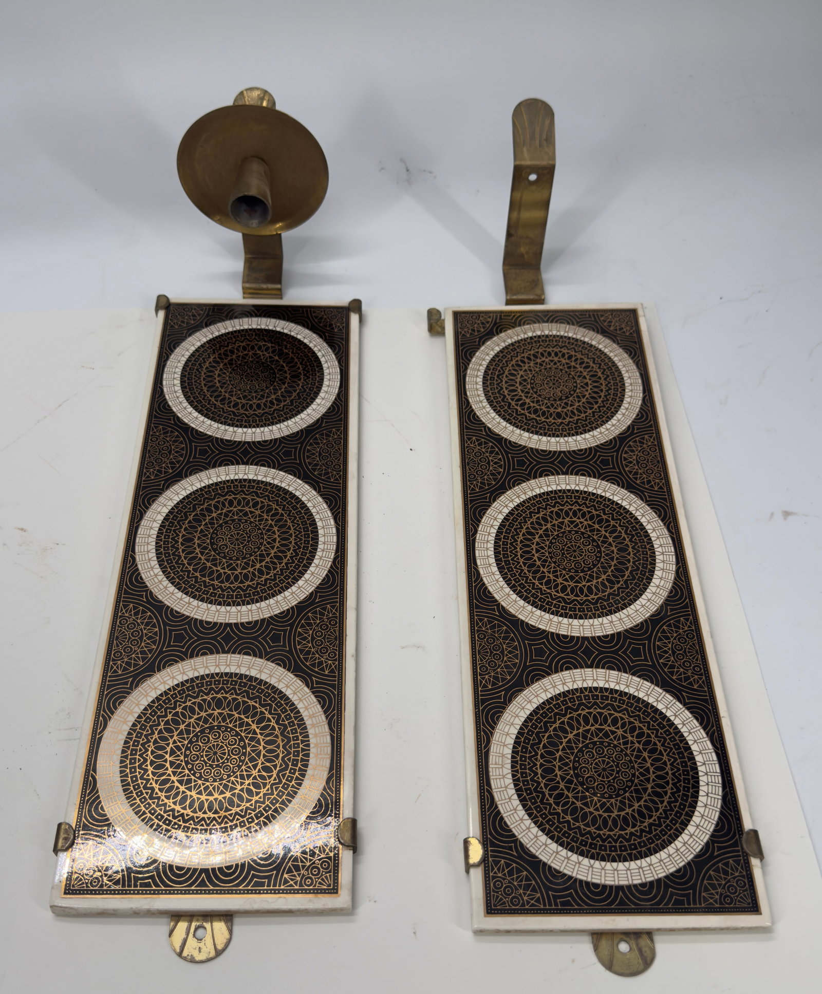 Pair Mid-Century Modern German Ceramic Wall Sconces: Vintage pair of West German wall sconces featuring rectangular ceramic panels with bold geometric circular designs in brown, black, and cream. Each sconce has a brass-tone candle holder and is marked 