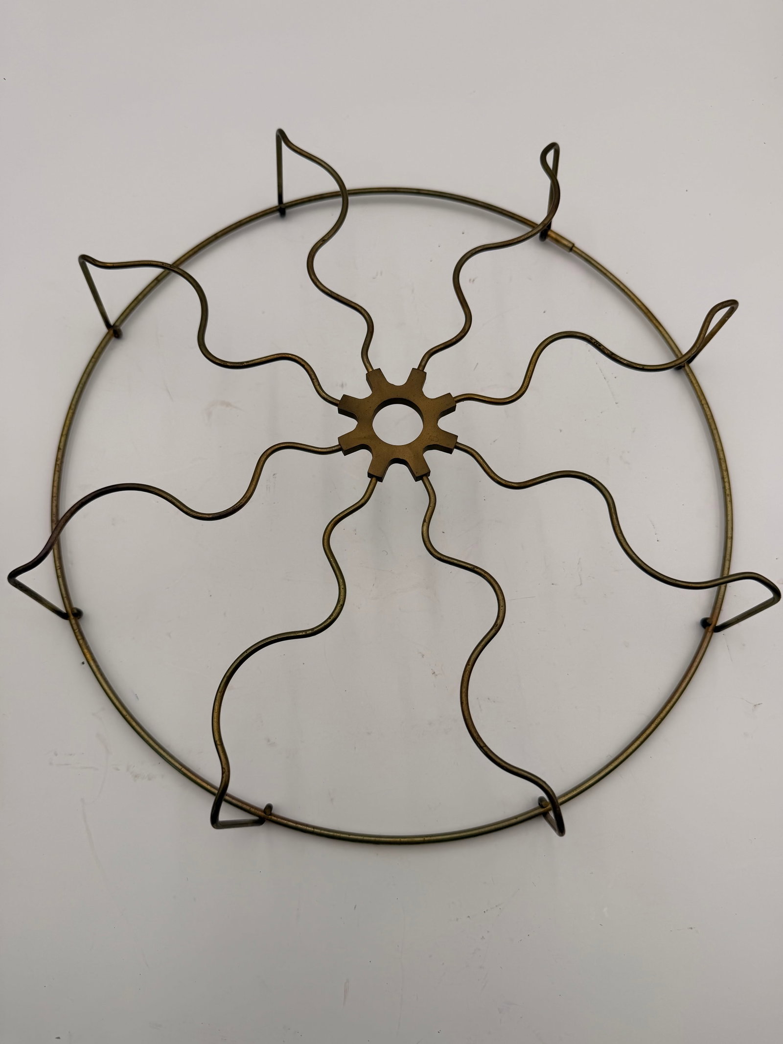 Antique Brass Electric Fan Front Guard: Original brass front guard from an early electric desk fan featuring a distinctive gear-shaped cast center hub with wavy wire spokes and a brass outer ring. Unmarked, but typical of fans produced in