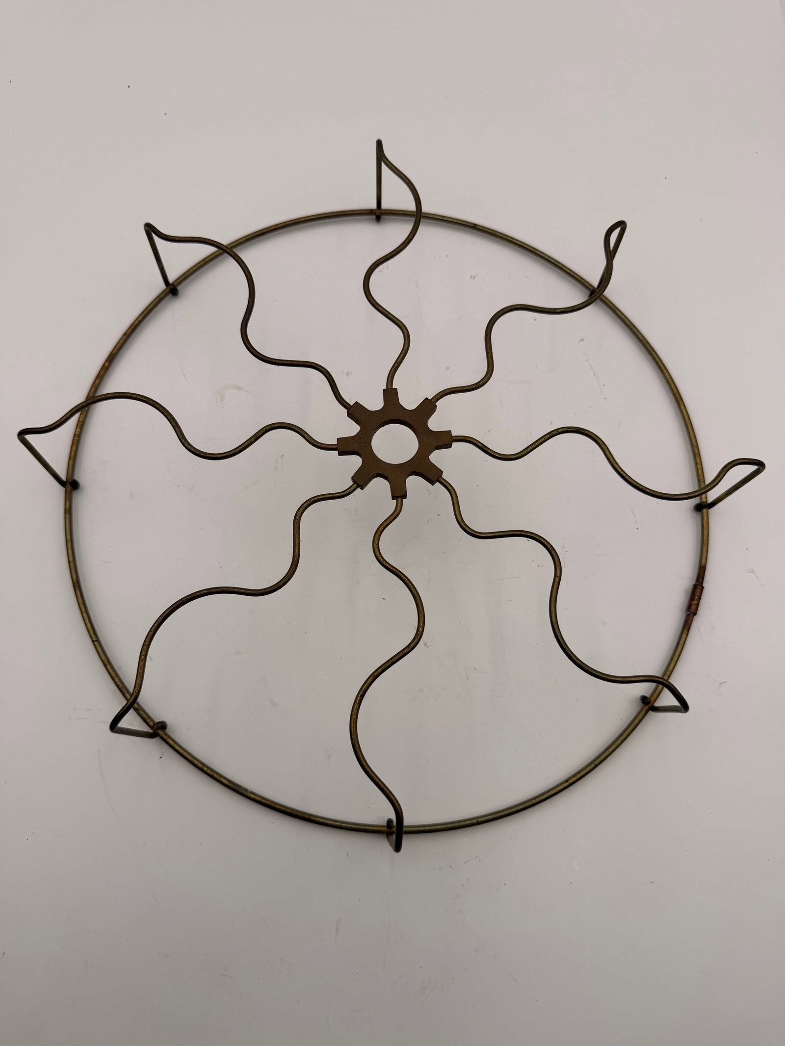 Antique Brass Electric Fan Front Guard: Original brass front guard from an early electric desk fan featuring a distinctive gear-shaped cast center hub with wavy wire spokes and a brass outer ring. Unmarked, but typical of fans produced in t