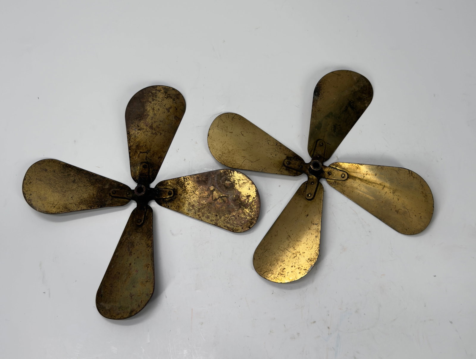 Pair Antique 4-Blade Brass Electric Fan Blades c.1905–1925: Matched pair of antique 4-blade brass electric fan blade assemblies with original brass blades and steel hubs. Features riveted construction and an aged patina from decades of use. Ideal for restorati