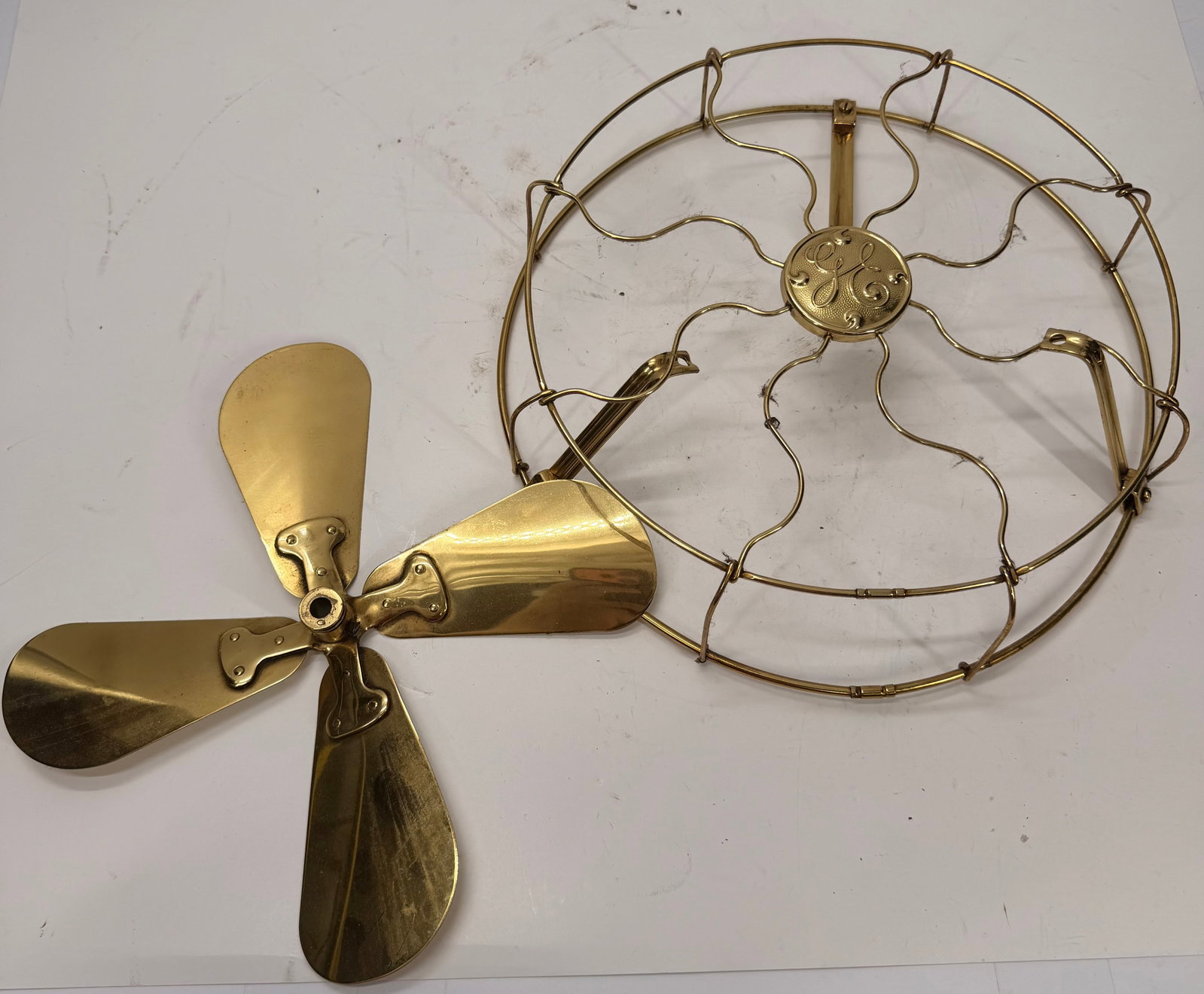 Vintage GE Brass Fan Cage & 4-Blade Brass Fan Blade Set for 12” Desk Fan: Original General Electric (GE) brass fan cage and matching 4-blade brass fan blade from a vintage 12-inch oscillating desk fan, dating to the early 20th century. The cage features the embossed GE mono
