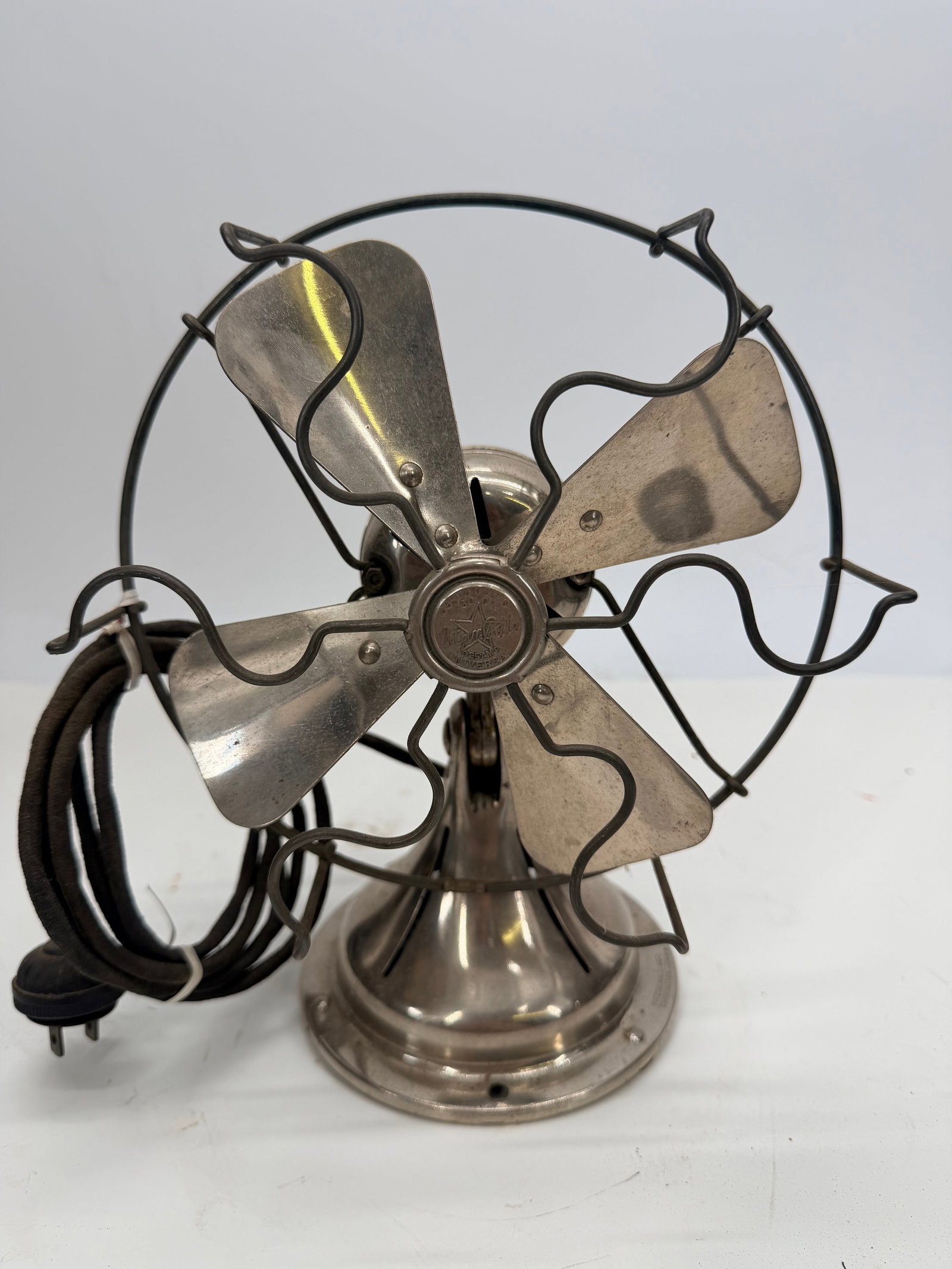 Vintage Fitzgerald Star Rite 4-Blade Electric Tabletop Fan, Cloth Cable: An early electric desk fan by Star-Rite, finished in nickel-plated metal with a tapered column and shaped base. The four-blade rotor sits within an open wire cage featuring decorative scrollwork trim.