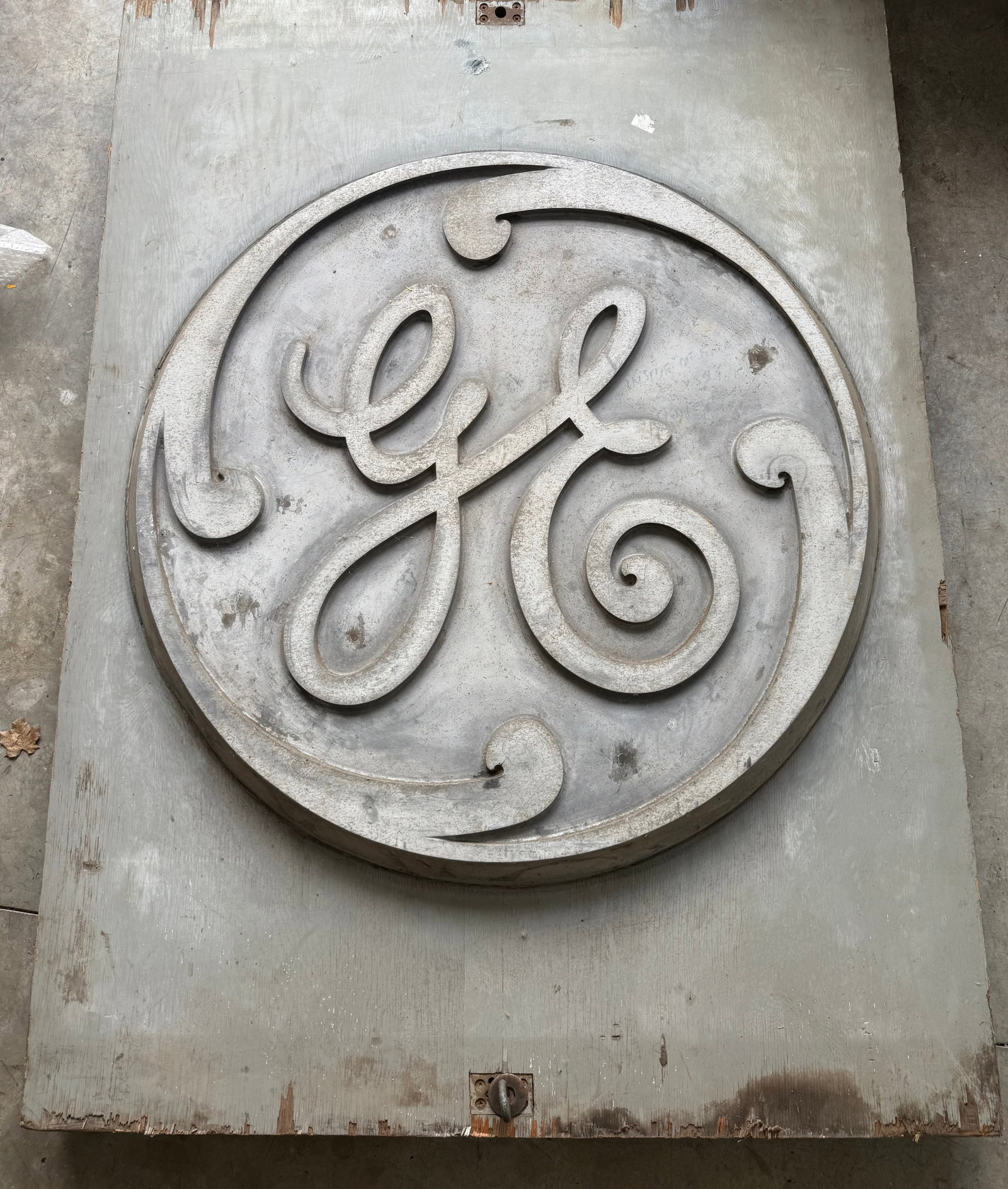 vintage General Electric (GE) company logo, likely a foundry mold or building sign.: This is a vintage General Electric (GE) company logo, likely a foundry mold or building sign.The logo features the iconic stylized "GE" monogram inside a circle with decorative flourishes.very heavy l