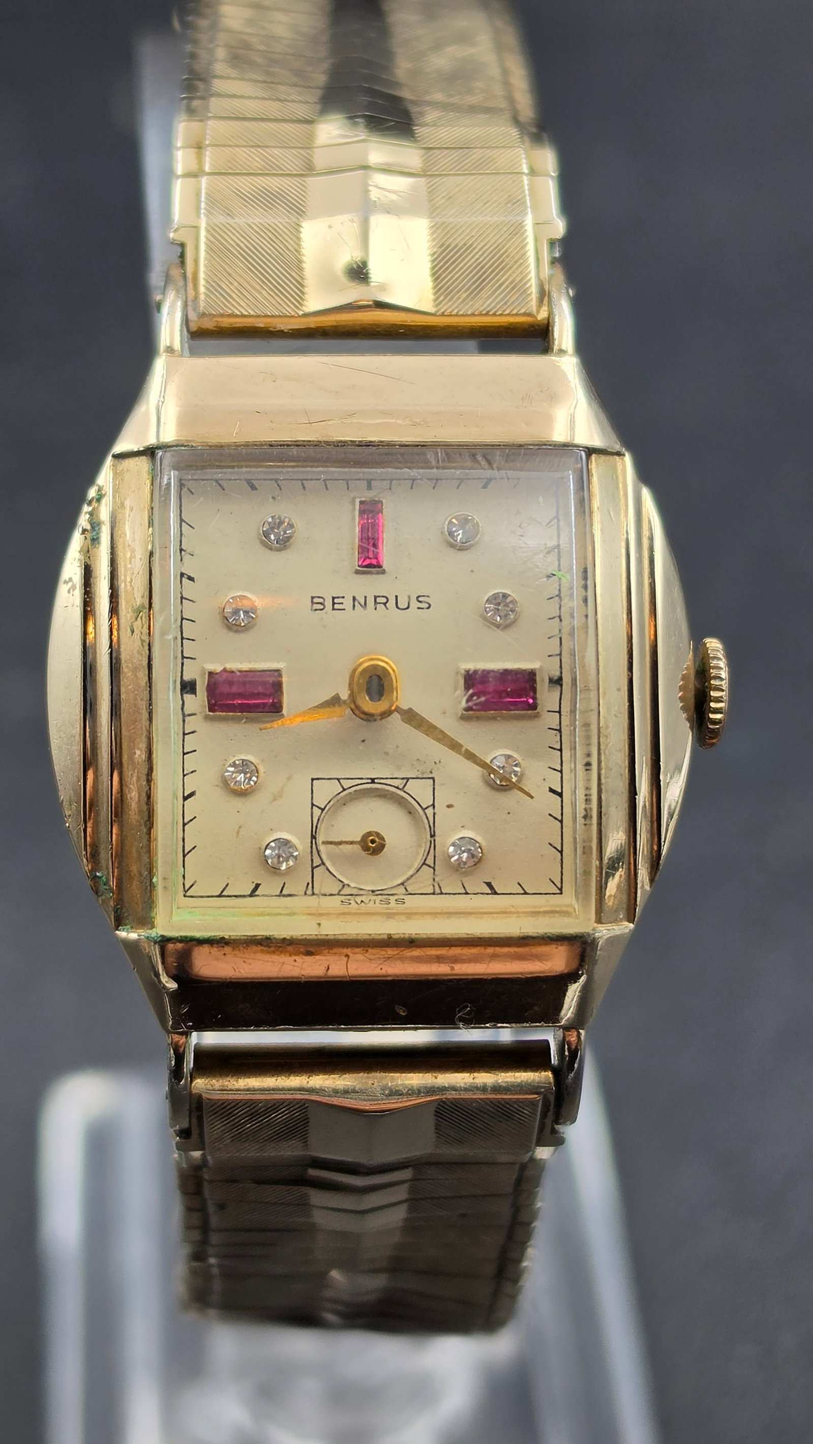Vintage Benrus Rectangular Wristwatch Ruby and Diamond Accent Dial Swiss Movement: This is a vintage Benrus wristwatch in a rectangular case with stepped, tapered lugs. The dial is signed Benrus with ruby baguette markers at the 12, 3, and 9 positions and round faceted clear accent 