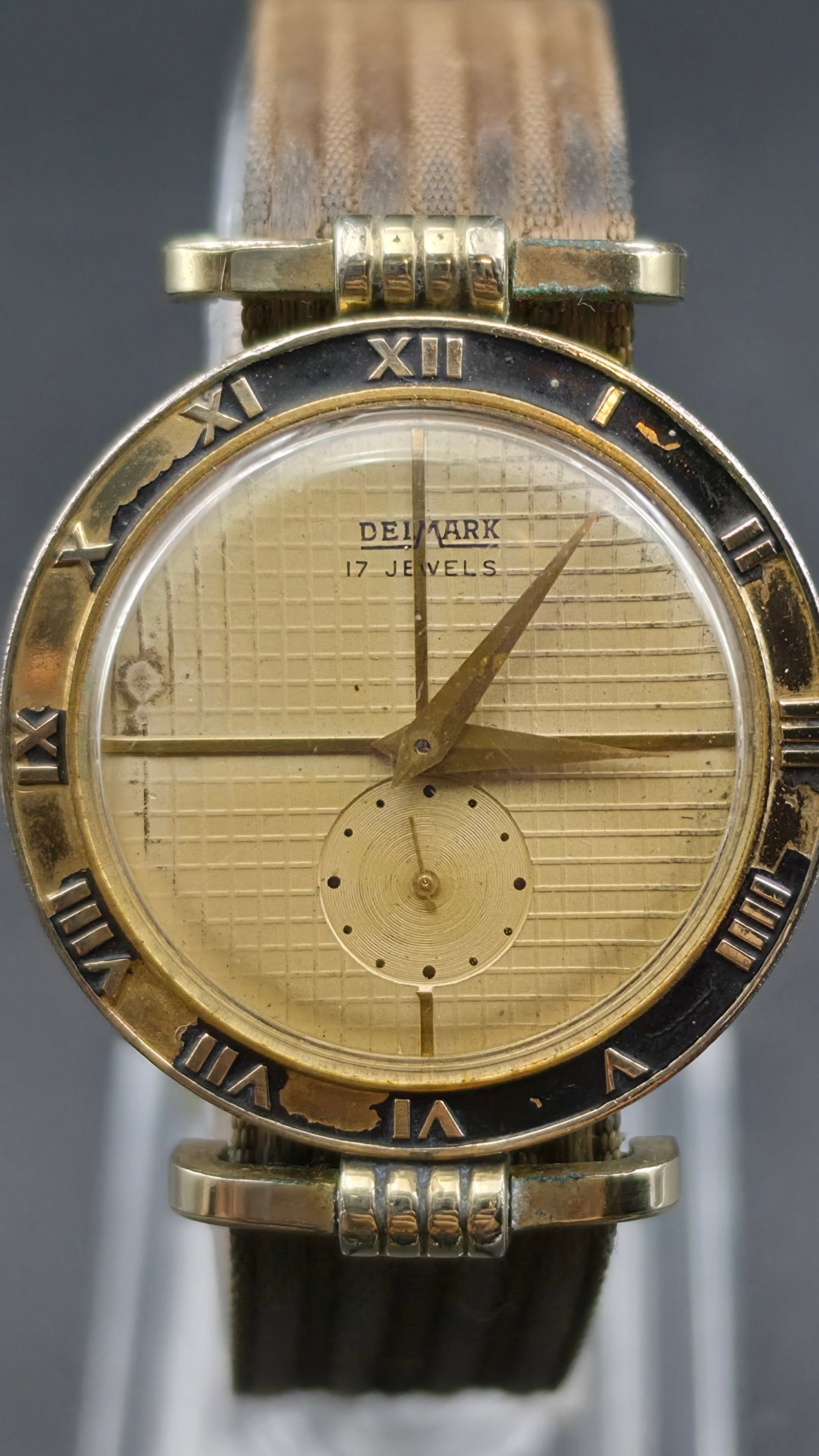 Vintage Mid-Century Delmark 17 Jewel Swiss Watch, Roman Numeral Bezel, Textured Dial, Sub-Seconds, R: This is a vintage Delmark wristwatch with a champagne textured waffle-pattern dial signed "Delmark, 17 Jewels," a sub-seconds register below center, and gold dauphine-style hands. The case features a 