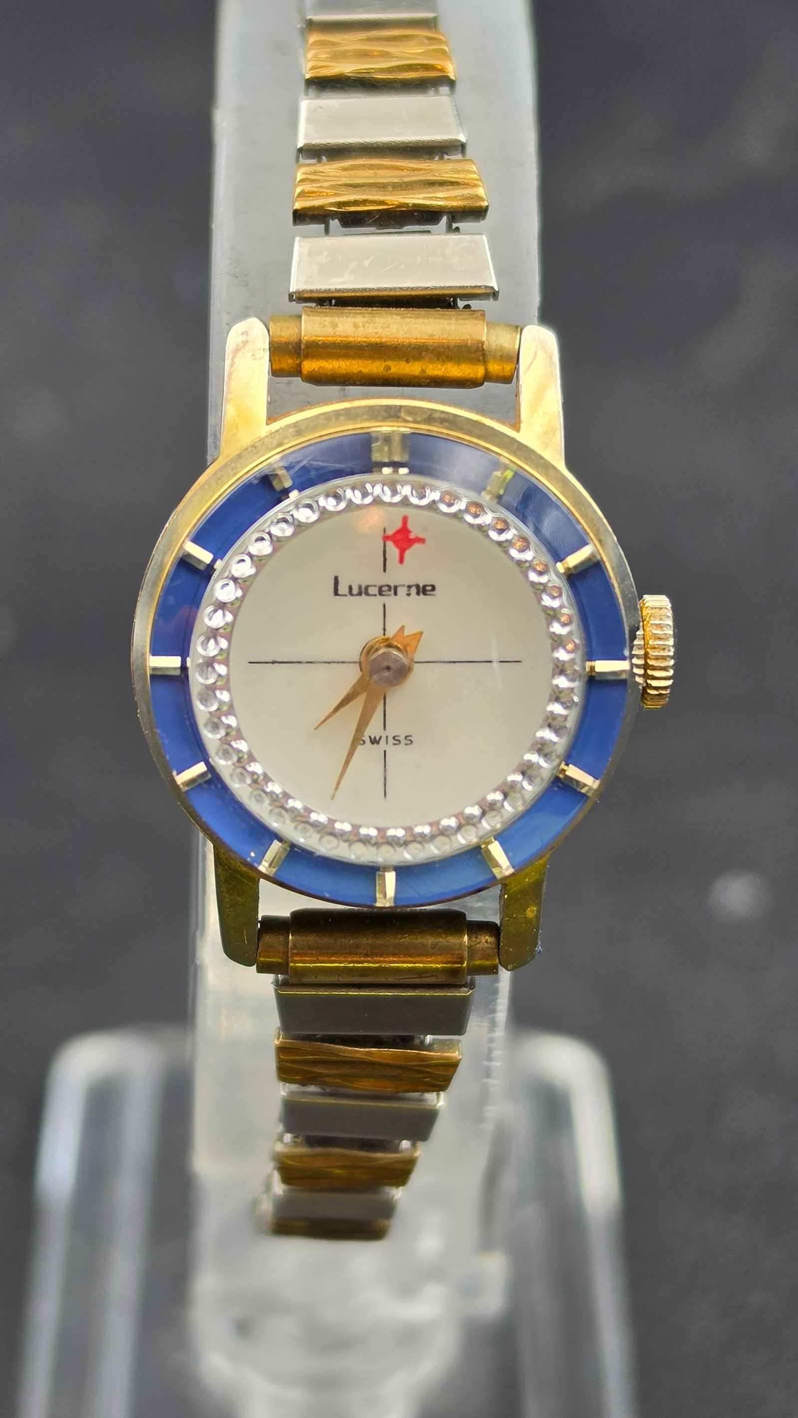 Vintage Lucerne Swiss Ladies Watch Blue Enamel Bezel Rhinestone Accent: vintage Lucerne Swiss ladies wristwatch in a two tone gold and silver tone case with a blue enamel style bezel ring surrounded by a circle of clear rhinestone accents. The white dial has a crosshair d