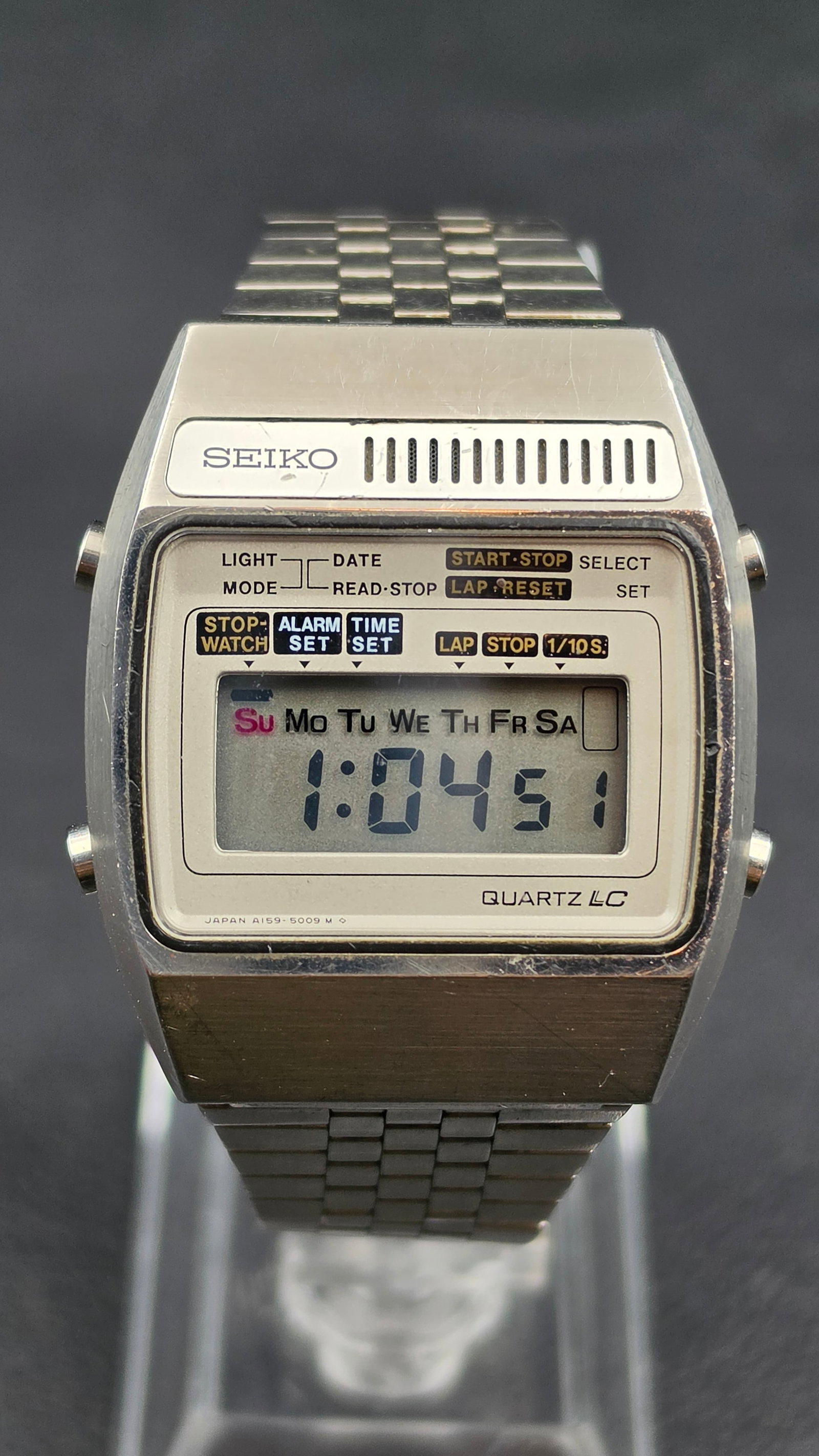 Seiko A159-5009 Quartz LC Digital Alarm Chronograph Watch 1978: A vintage 1978 Seiko Quartz LC digital wristwatch, case width measuring 34.67mm, in a stainless steel case with an integrated bracelet. The LCD display shows time, day of the week, and includes stopwa