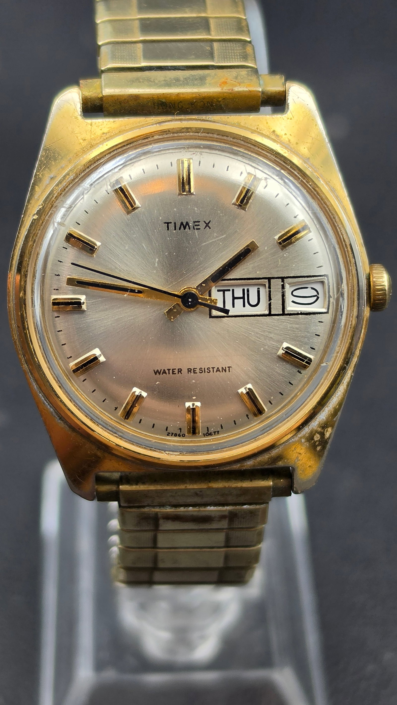 Vintage 1977 Timex Marlin Day Date Watch Gold Tone Mechanical 27860 10677 34mm: This is a vintage Timex Marlin day date wristwatch, reference 27860 10677, dated to 1977 by its model number. The case is gold tone with a base metal bezel and a stainless steel case back, marked BASE