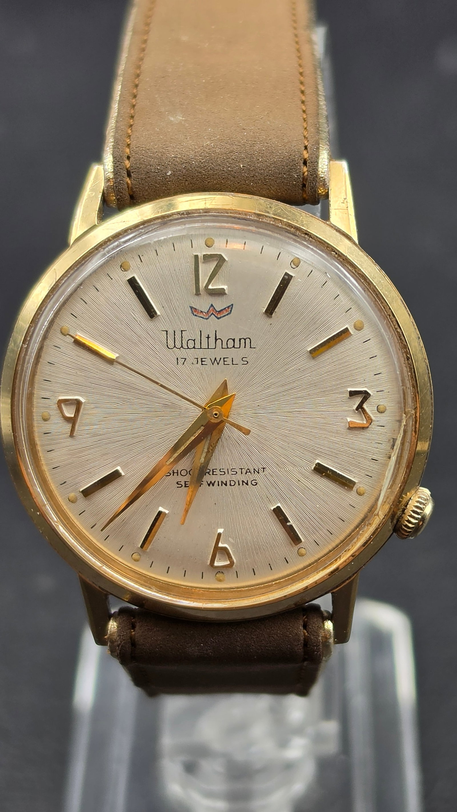 Waltham 17 Jewels Selfwinding Watch Gold Tone Case Running: This is a vintage Waltham automatic wristwatch with a gold tone base metal bezel and stainless steel back. The silver sunburst dial is signed Waltham, 17 Jewels, Shock Resistant, and Selfwinding, with