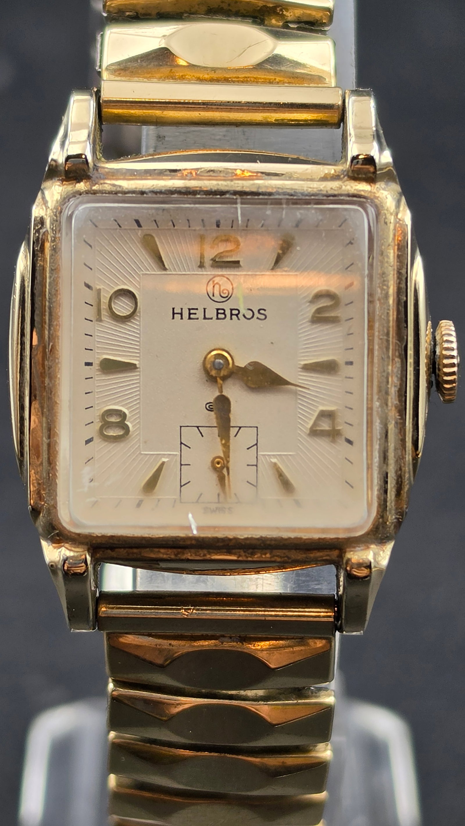 Helbros 1950s 17 Jewel Cal 101 Mens Wristwatch, 10K RGP Bezel, Stainless Steel Back, Expansion Band: This is a 1950s Helbros Watch Co. men's wristwatch in a cushion-shaped case measuring approximately 28mm wide excluding the crown, with a 10K rolled gold plate bezel and stainless steel case back. The