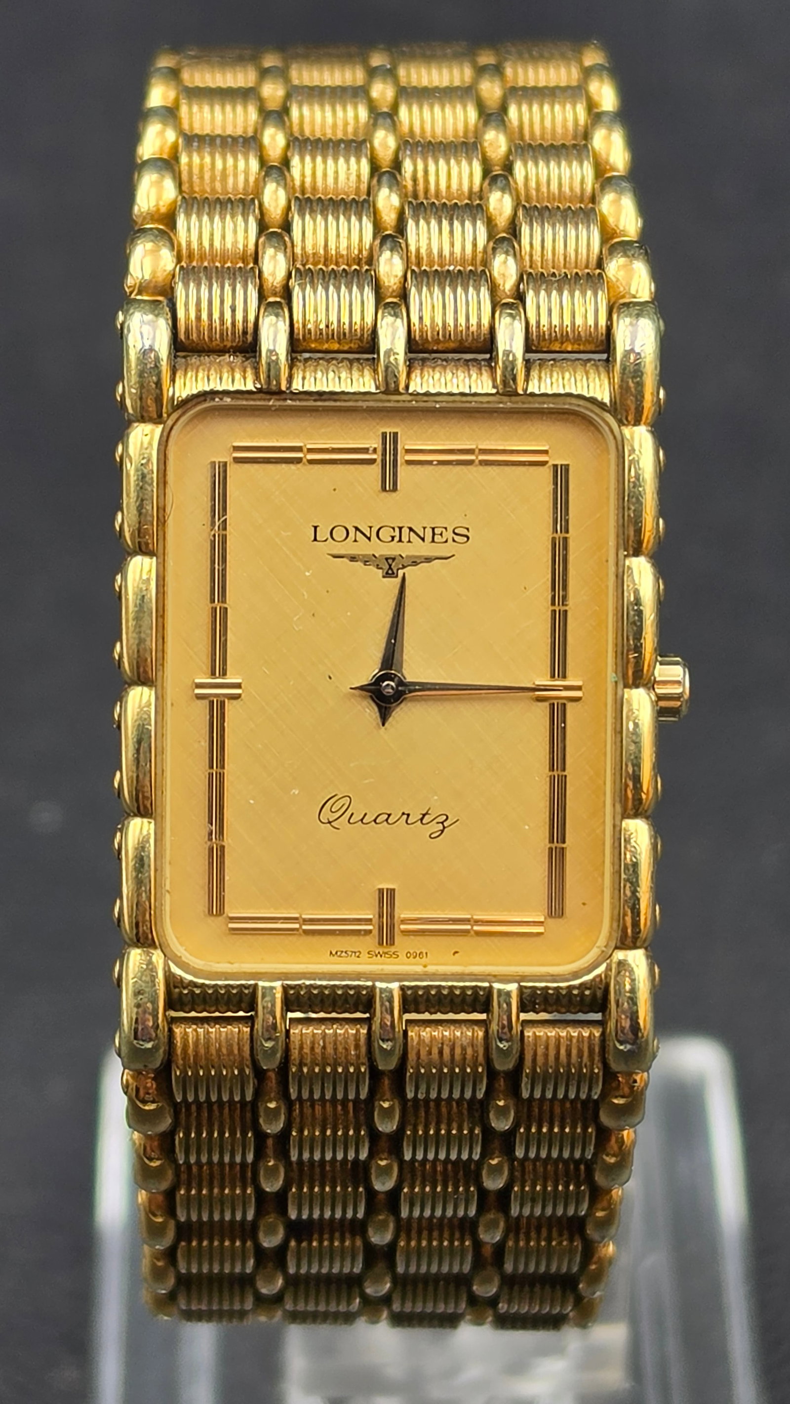 Longines Quartz MZ5712 Gold Tone Rectangular Mens Watch, Swiss Made: This is a Longines Quartz wristwatch, reference MZ5712 SWISS 0961, in a rectangular gold-tone base metal case measuring approximately 23.63mm wide excluding the crown. The dial is signed Longines with