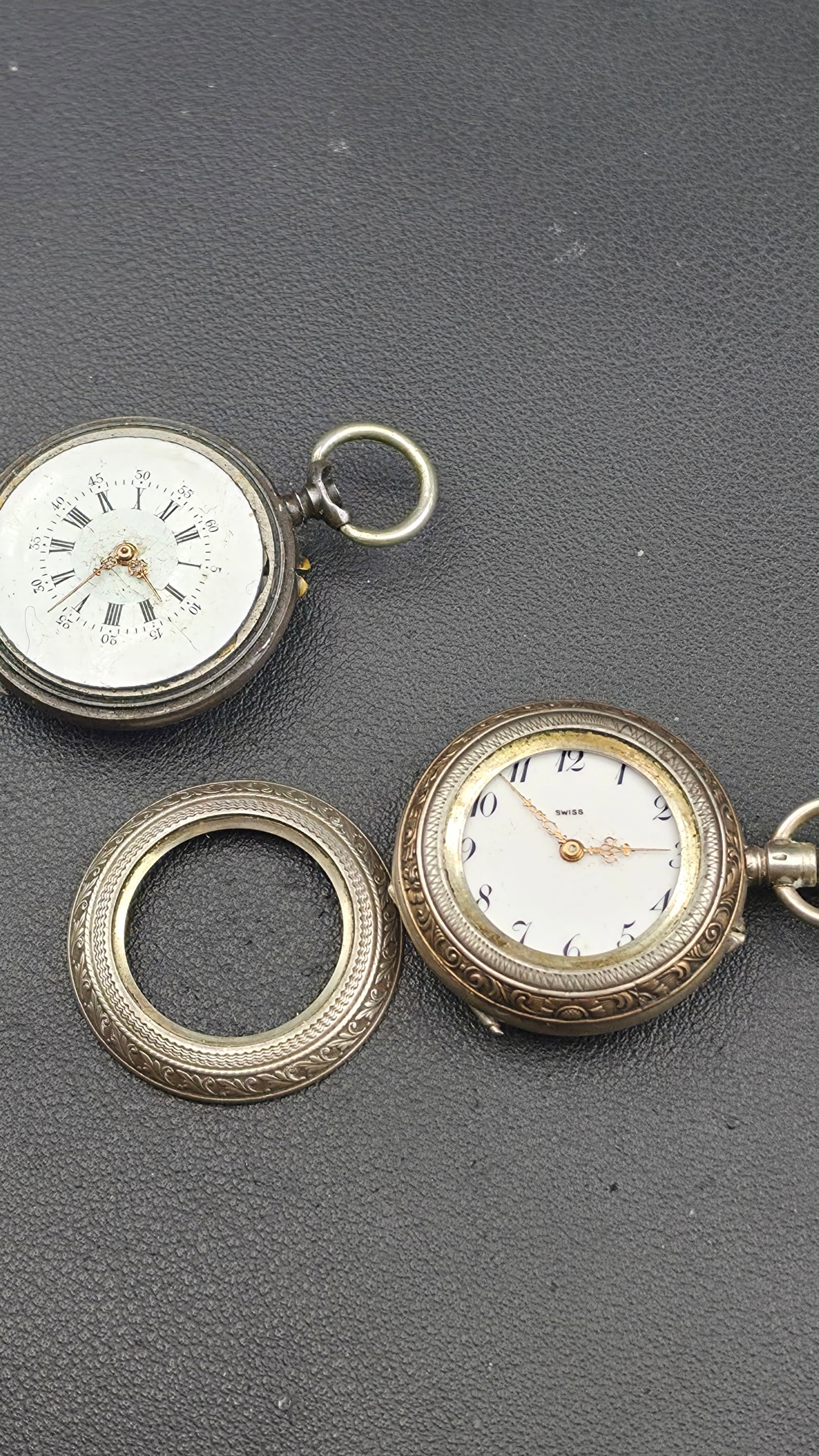 Antique Silver Pocket Watch Parts Lot, Two Fob Watch Heads with Engraved Cases and Loose Bezel Rings: This lot includes two small antique fob pocket watches along with two loose engraved case rings, offered as an untested parts or restoration group. The first watch has a case stamped 0.800 with a P&M 