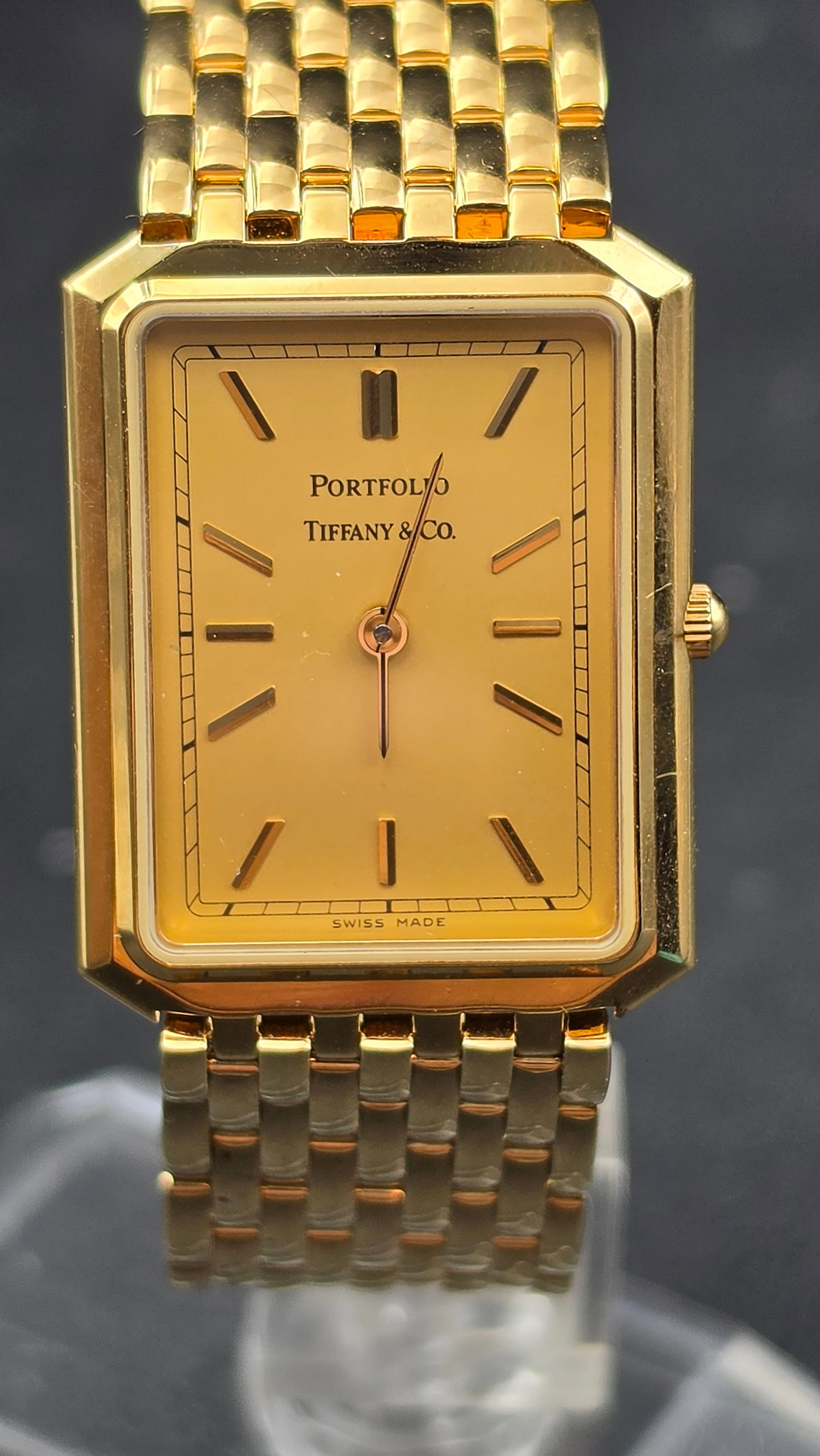 Portfolio by Tiffany & Co. Gold Electroplated Quartz Watch Full Set New Battery: This Portfolio by Tiffany & Co. wristwatch features a rectangular case with a champagne dial, applied baton hour markers, and blued sword-style hands, signed Portfolio Tiffany & Co. and Swiss Made. Th