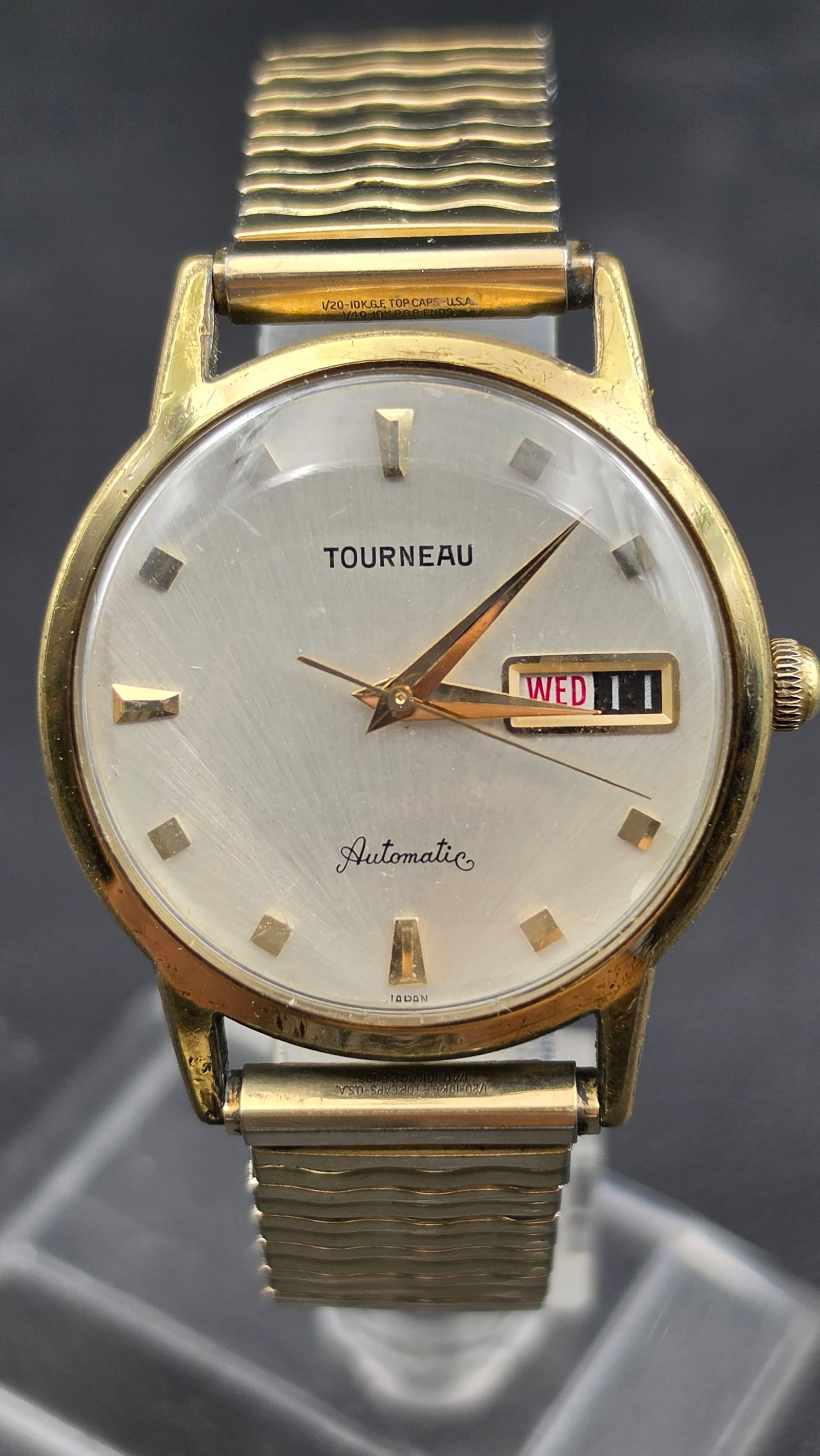 Vintage Tourneau Automatic Day-Date Watch 10K GF Top Running: This is a vintage Tourneau Automatic day-date wristwatch with a silvered dial featuring applied gold-tone faceted hour markers, gold-tone dagger hands, and a day/date window with red Wednesday text at