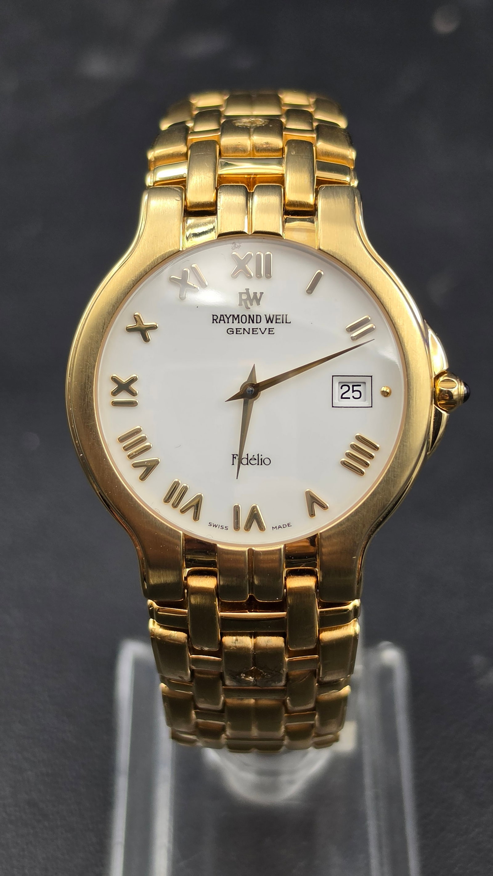 Raymond Weil Geneve Fidelio Ref. 9162 Sapphire Crystal Quartz Date Watch New Battery: This is a Raymond Weil Fidelio wristwatch, reference 9162, with a white dial featuring Roman numerals, the RW Fidelio signature, and a date window at 3 o'clock. The case measures approximately 33.4mm 