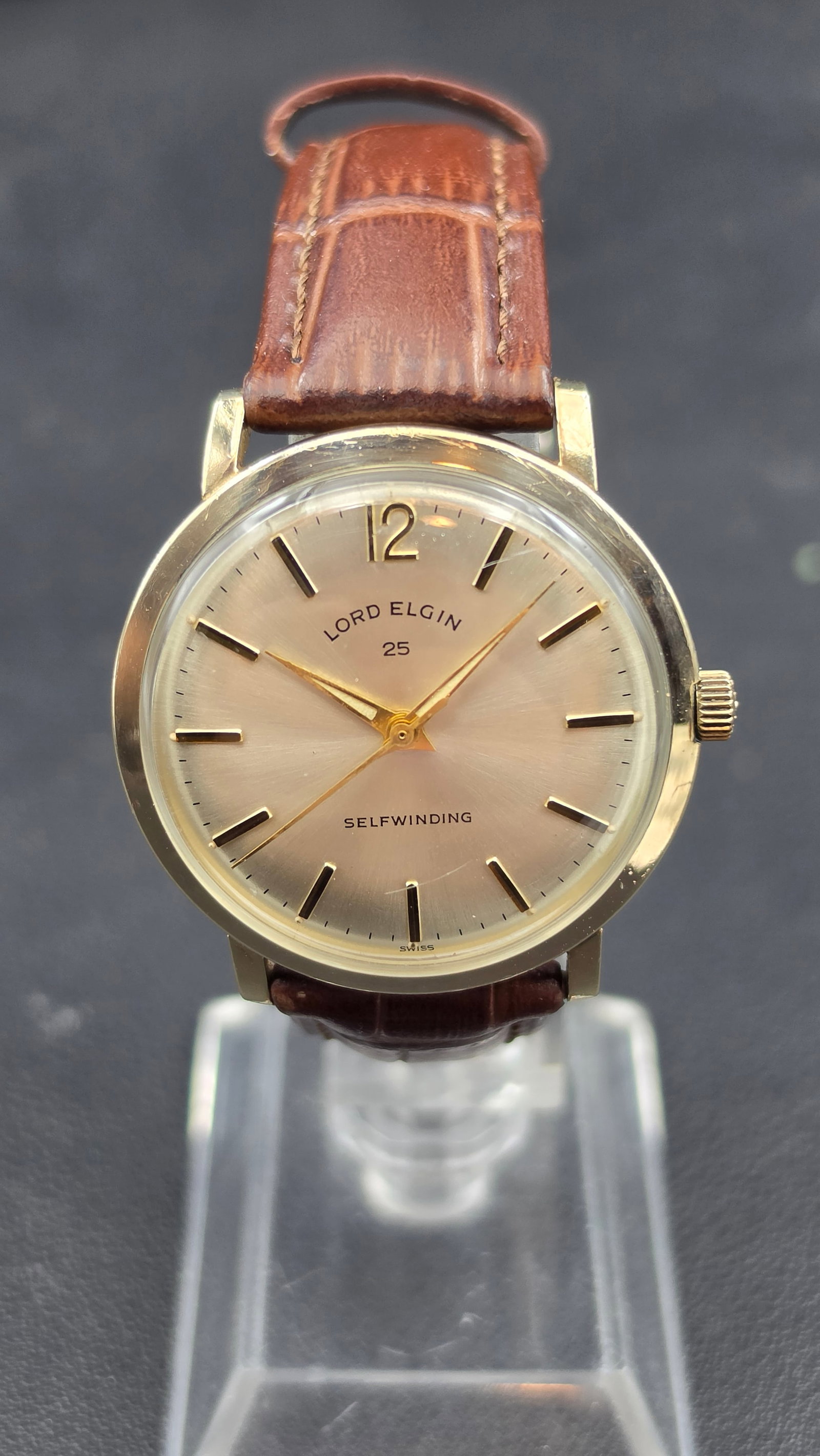 Vintage Lord Elgin 25 Jewel Selfwinding Automatic Men's Watch, Cal. 884, Swiss Made: This vintage Lord Elgin wristwatch features a silver dial signed "Lord Elgin 25" and "Selfwinding," with applied gold-tone baton markers, an Arabic 12, and dauphine hands. The case back is stamped "Ba