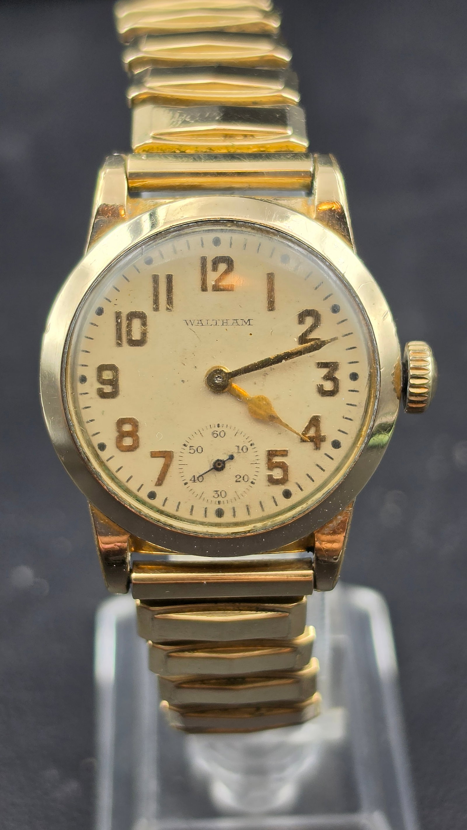 Vintage Waltham 15 Jewel Wristwatch, 10K Rolled Gold Plate Case: This vintage Waltham wristwatch features a cream dial signed "Waltham," with applied gold-tone Arabic numerals, blued steel hands, and a subsidiary seconds register at 6 o'clock. The case back is mark