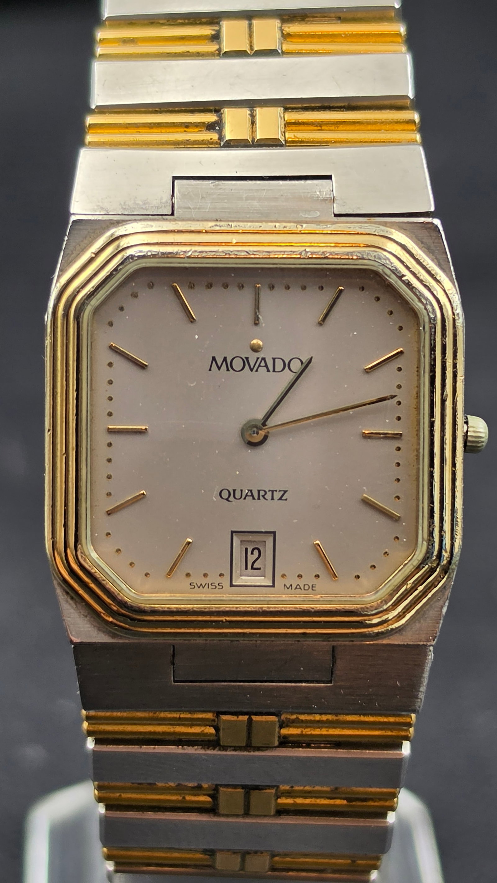 Vintage Movado Quartz Two-Tone Ladies Watch, Ref. 81-42-350, Swiss Made: This vintage Movado wristwatch features a square case with cut corners and a cream dial signed "Movado" and "Quartz," with applied gold-tone baton markers and a date window at 6 o'clock. The two-tone 