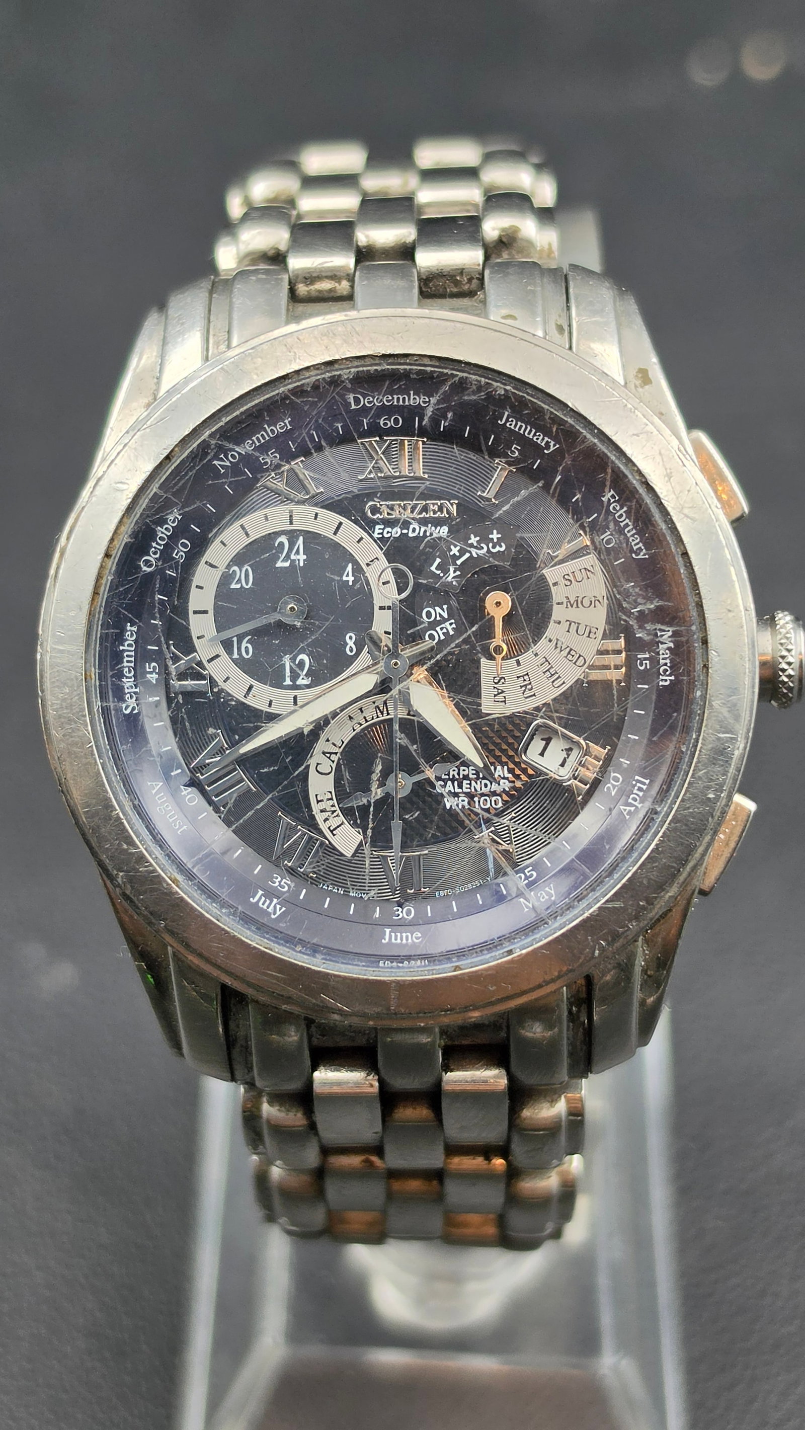 Citizen Eco-Drive Perpetual Calendar Chronograph Alarm Watch, Ref E670, WR100, Box & Papers: This Citizen Eco-Drive Perpetual Calendar chronograph features caliber E670, reference E670-S028251, with a black multi-dial layout showing Roman numeral hour markers, a rotating month/date perpetual 