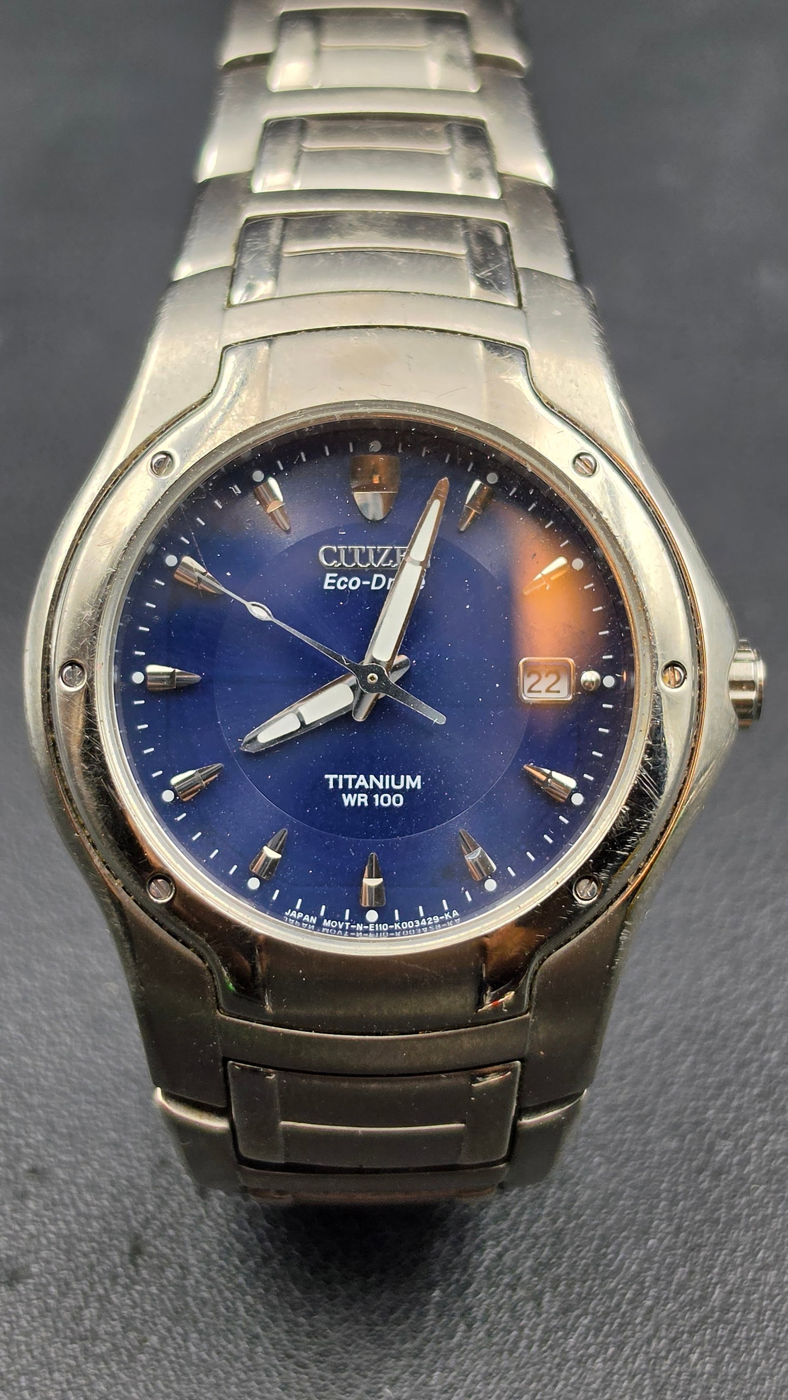 Citizen Eco-Drive Titanium Wristwatch, Blue Dial, WR100, Box & Papers: This Citizen Eco-Drive wristwatch features a titanium case and bracelet with a blue sunburst dial signed Citizen Eco-Drive, Titanium, WR100, applied baton markers, and a date window at 3 o'clock, with