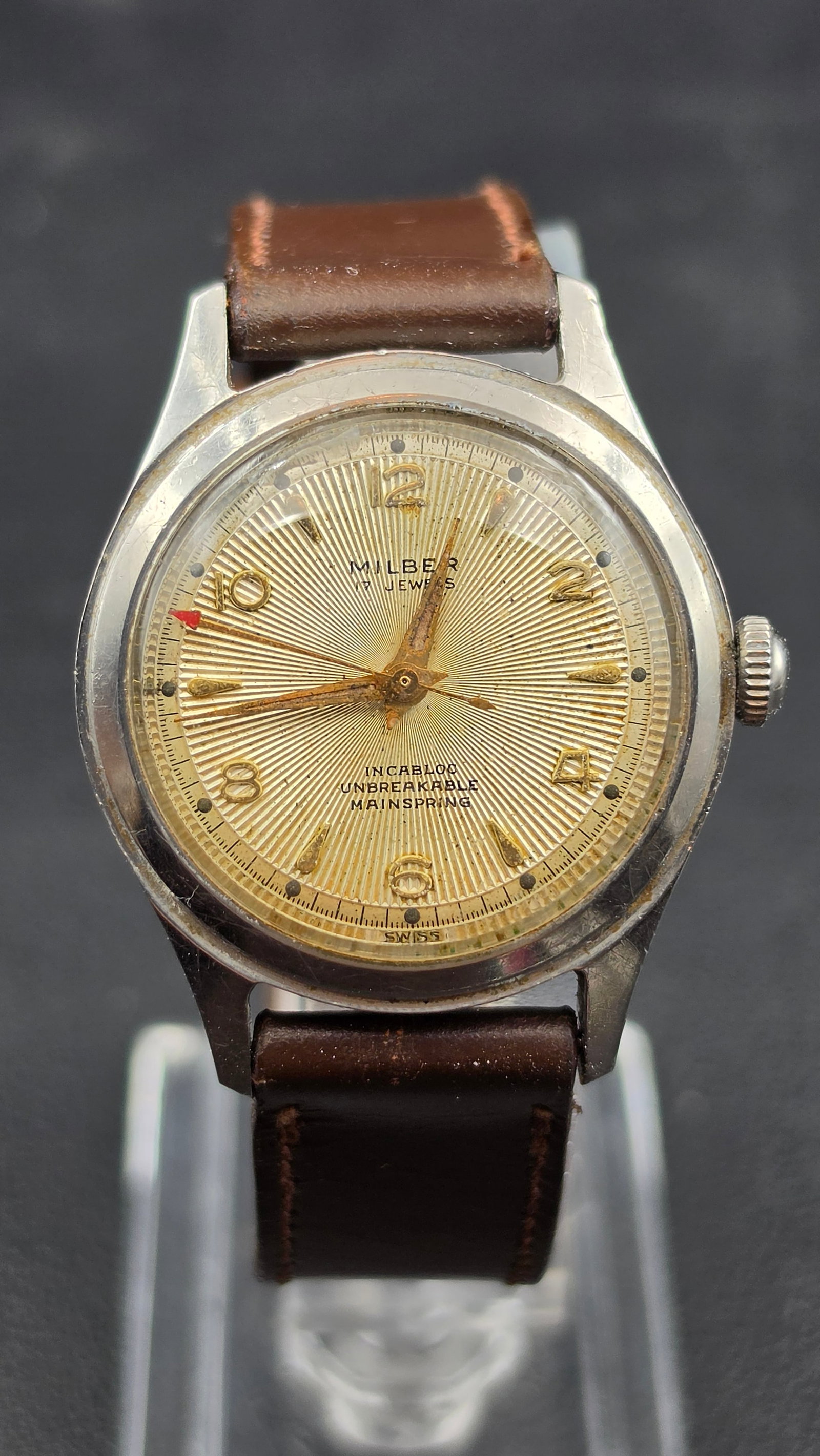 Vintage Milber 17 Jewel Incabloc Swiss Watch Sunburst Dial 1950s: This is a vintage Milber watch, Swiss made, with a sunburst textured dial signed Milber 17 Jewels, Incabloc, Unbreakable Mainspring, and a red-tipped minute marker near 10. The movement is signed Seve