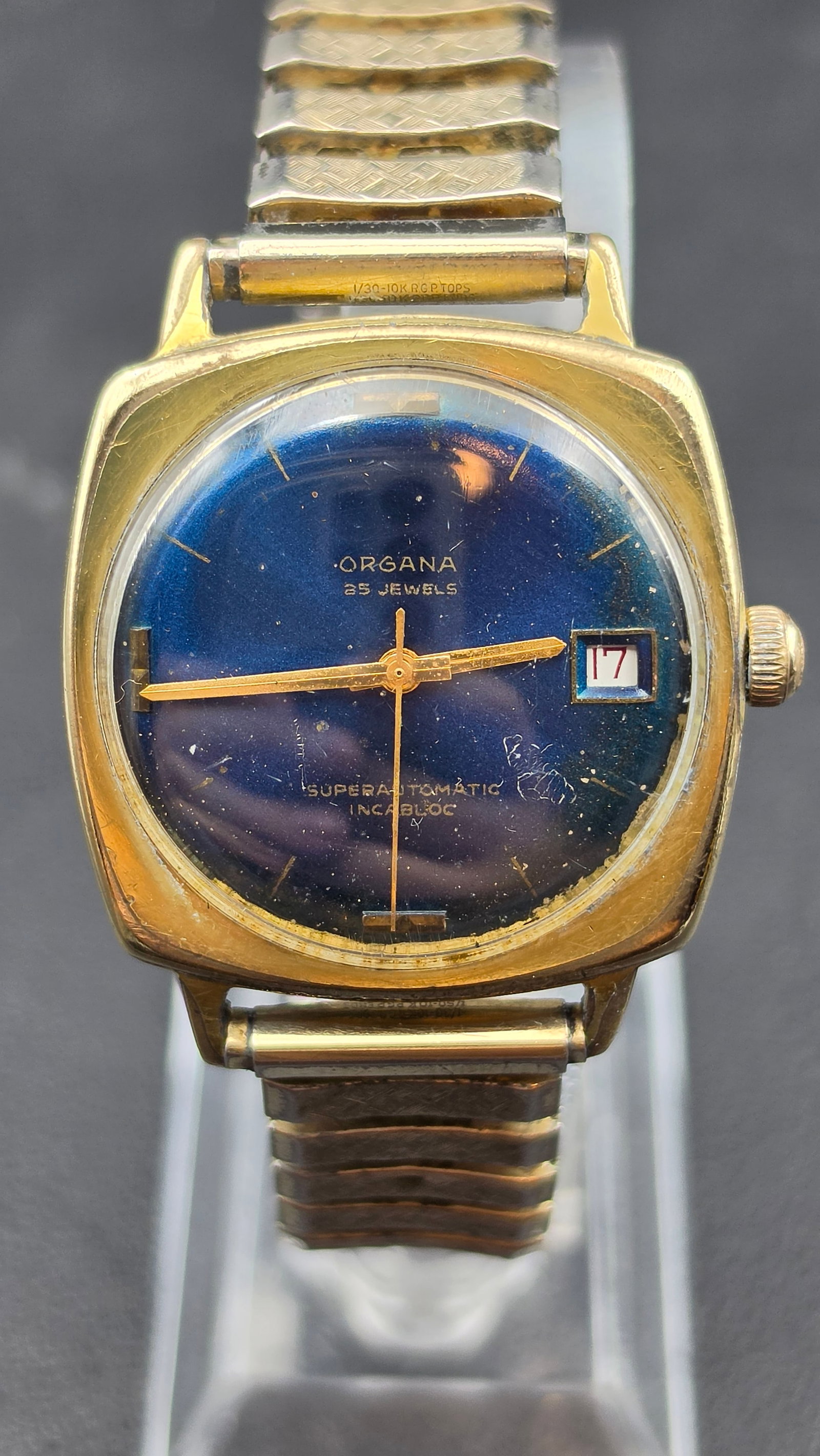 Vintage 1970s Organa Superautomatic 25 Jewel Blue Dial Watch Incabloc Date Running: This is a vintage Organa Superautomatic wristwatch in a gold-filled tonneau-shaped case, marked 10K R.G.P. on the case and band. The blue sunburst dial is signed Organa, 25 Jewels, Superautomatic, Inc