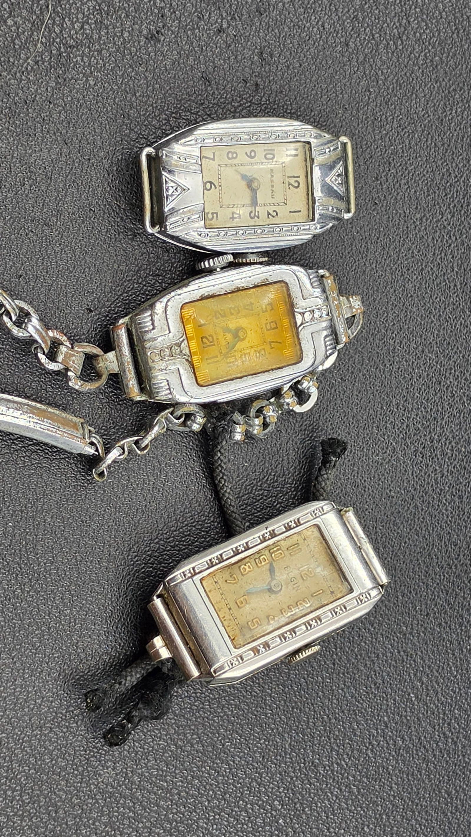 Small Lot of Vintage Art Deco Ladies Watches: This lot includes three vintage Art Deco ladies wristwatches in engraved rectangular cases. The first is signed Nassau, with a rectangular dial, engraved geometric case detailing, and a fixed link bra