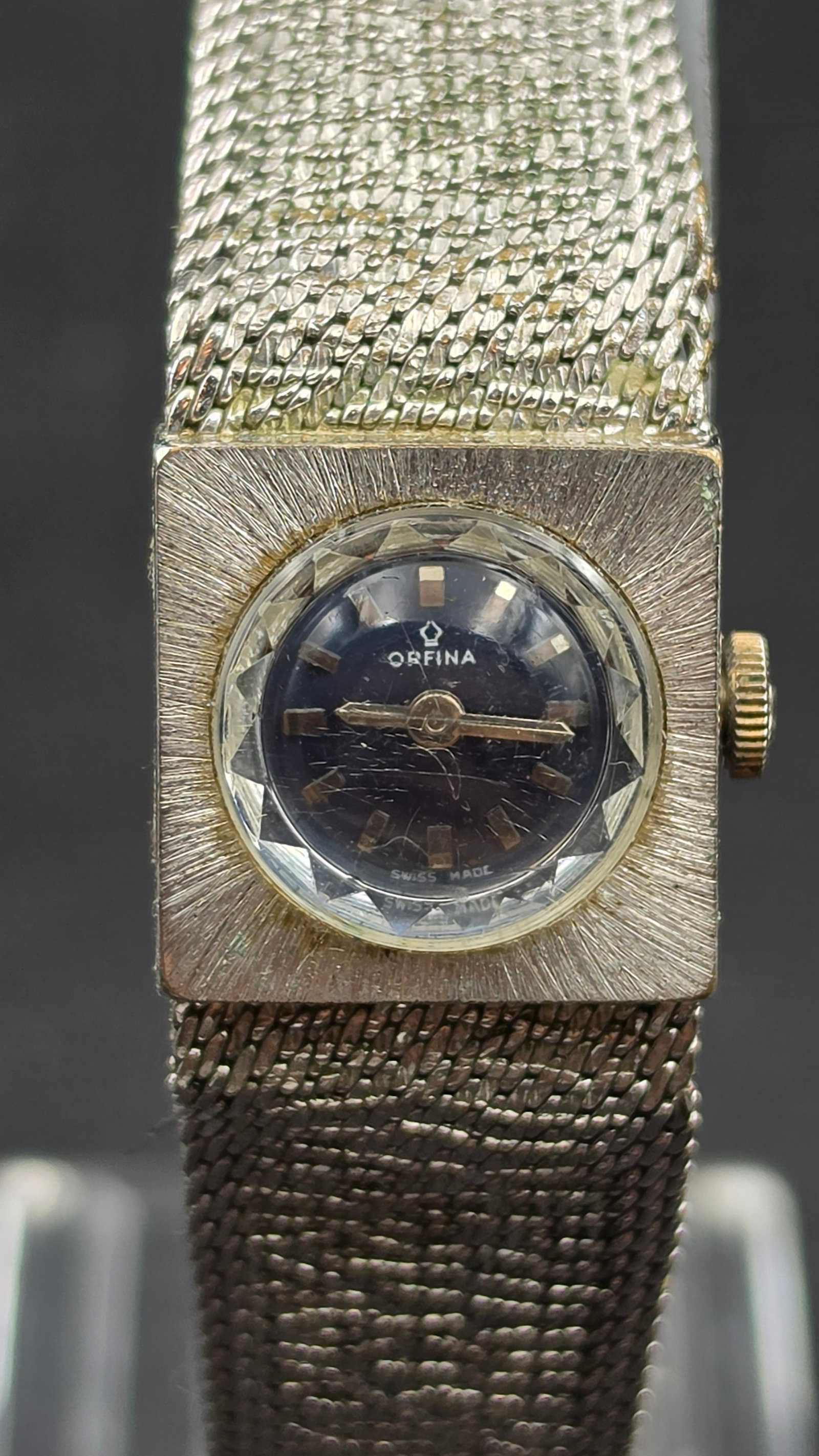 Vintage Orfina 17 Jewel Ladies Cocktail Watch, Faceted Crystal, Integrated Mesh Bracelet: This vintage manual wind ladies' watch is signed Orfina on a black dial with a faceted crystal and gold tone baton markers, in a square textured case on an integrated mesh bracelet. The case back is m