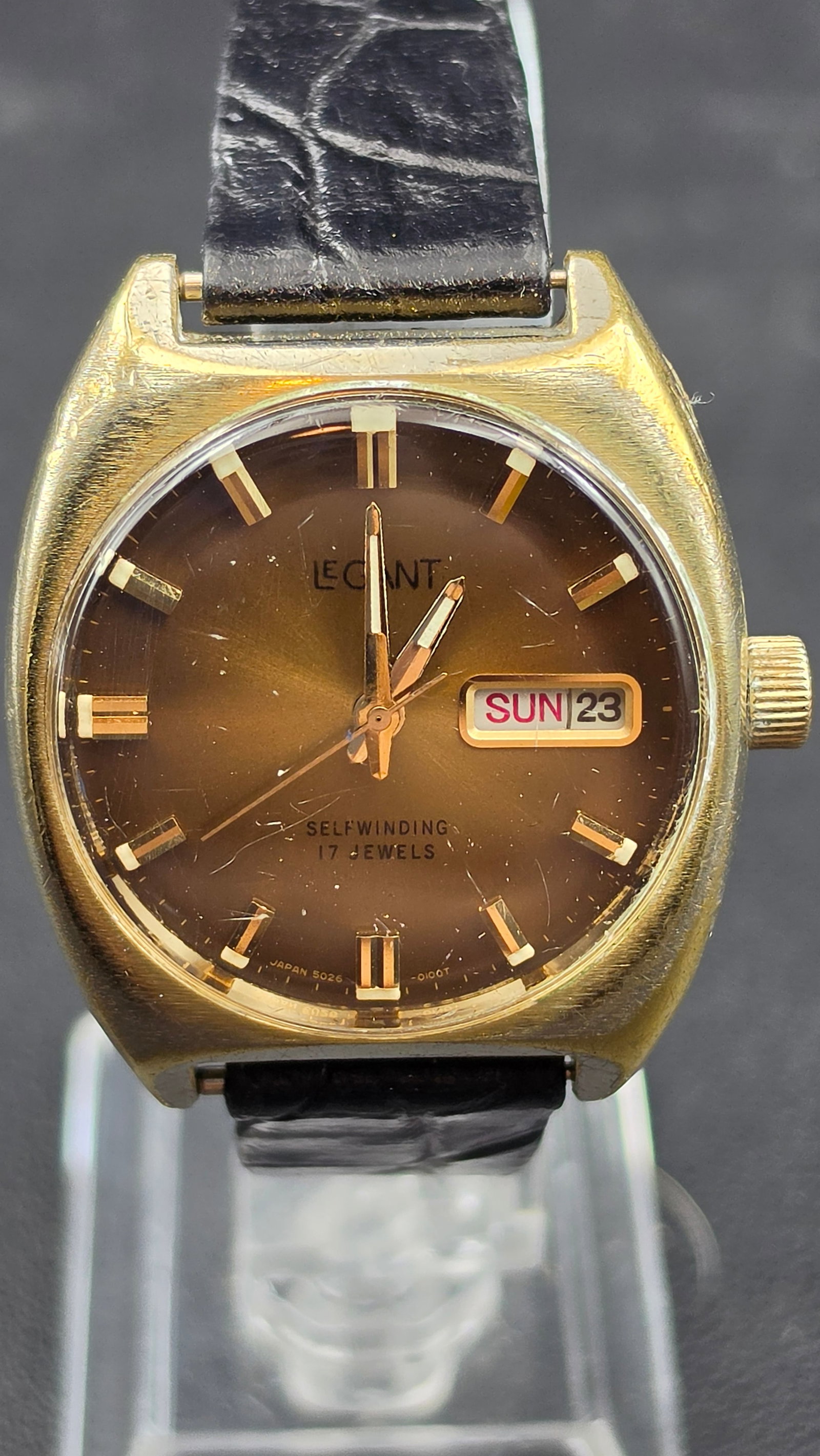 Vintage Legant Selfwinding 17 Jewel Day-Date Watch, Japan Movement: This vintage automatic wristwatch is signed Legant on a brown dial with Selfwinding 17 Jewels noted, a day-date window, and applied baton markers, marked Japan 5026-0100T. The case measures approximat