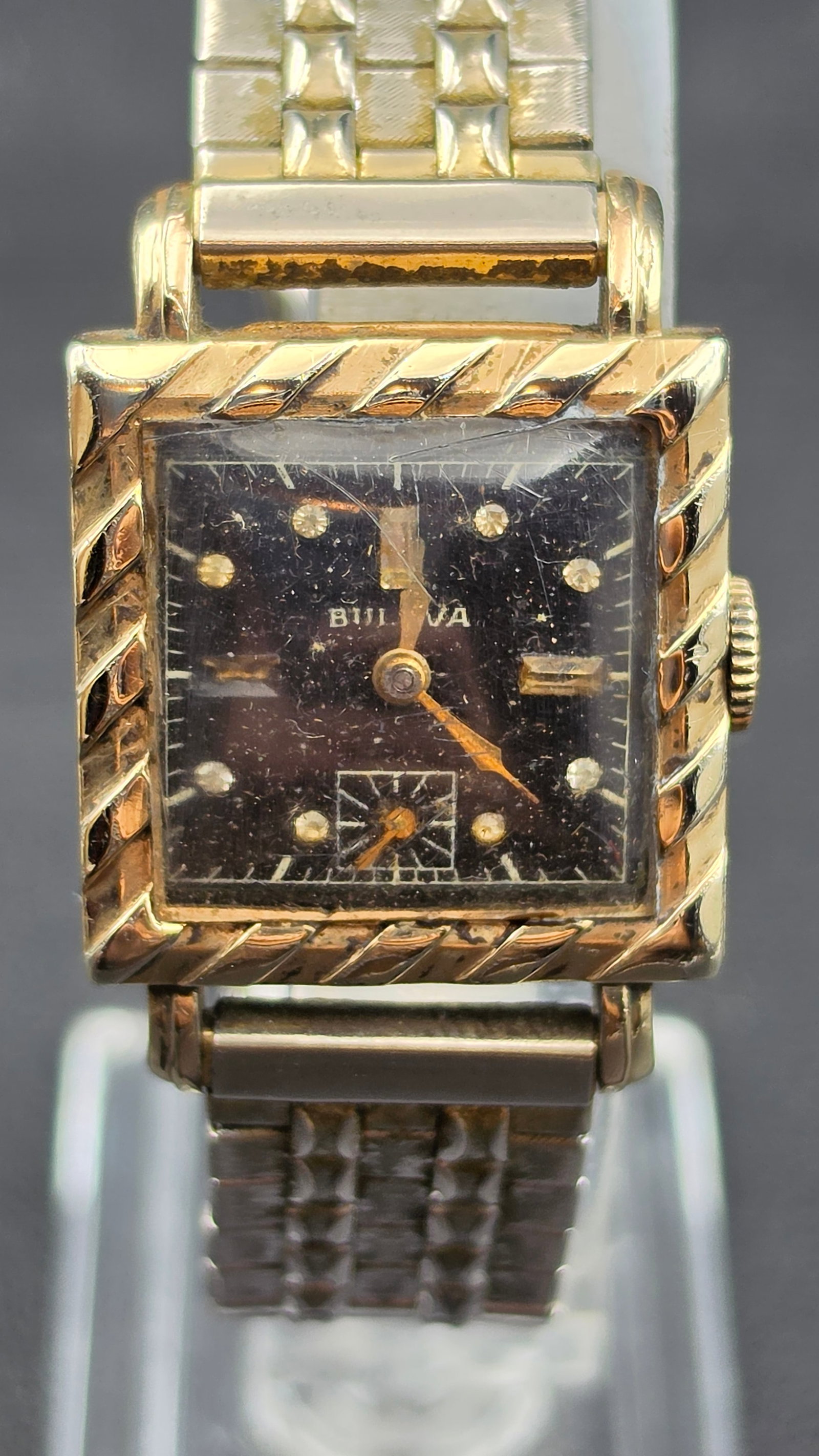 Vintage 1940s Bulova 15 Jewel Tank Watch 10K Rolled Gold Plate Bezel Running: This vintage Bulova tank-style wristwatch features a square case with a fluted, diagonal-cut 10K rolled gold plate bezel over a stainless steel back, stamped by Duro Watch Case Co. The black dial is s