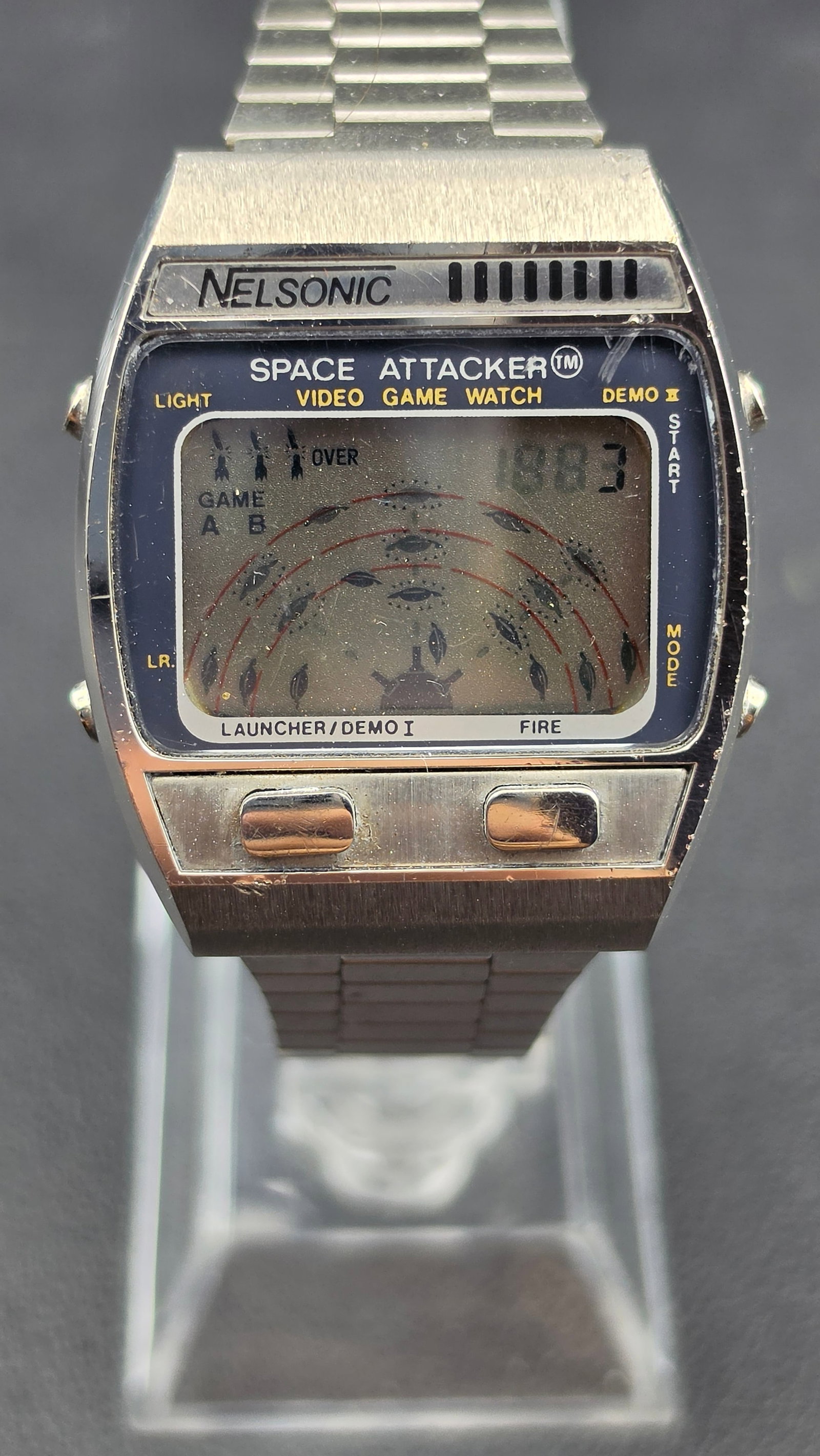 Vintage 1981 Nelsonic Space Attacker LCD Video Game Watch New Battery Working: This is a vintage Nelsonic Space Attacker LCD video game watch, produced by M.Z. Berger and Co. Inc. and made in Hong Kong. The stainless steel case houses an early-1980s multi-function module combini