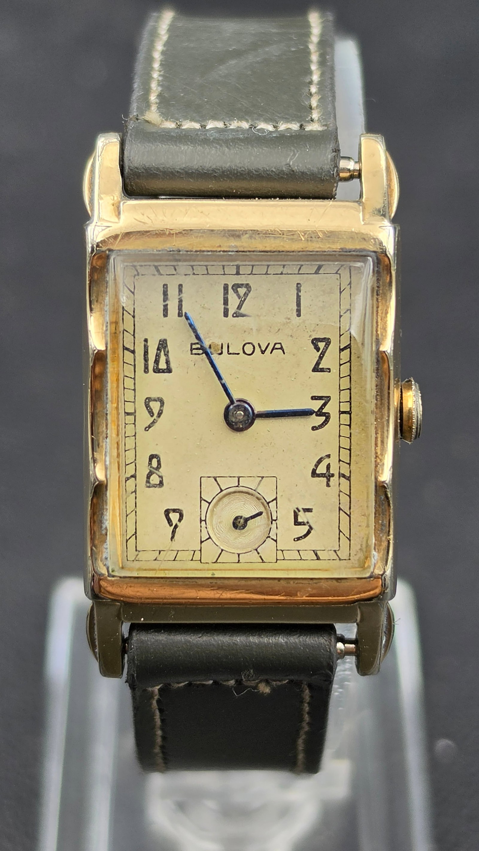 Vintage 1940s Bulova 21 Jewel 10K Gold Filled Rectangular Wristwatch Running: This vintage Bulova wristwatch has a rectangular tank-style case with a case back stamped 10K Gold Filled, Bulova, and a serial number. The dial is signed Bulova with blue steel hands and a sub-second