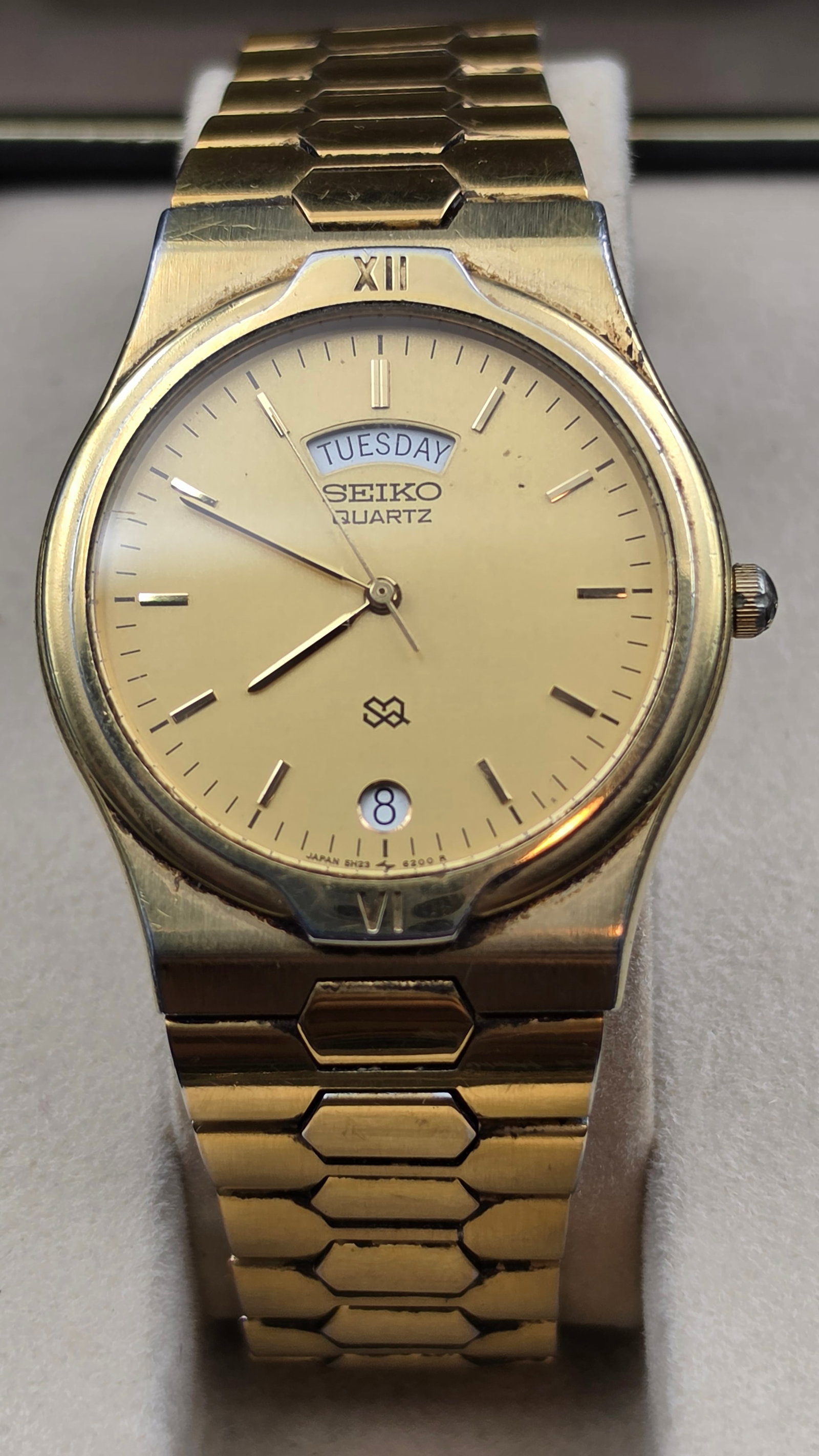 Seiko Quartz Day Date Gold Tone Watch SGF536 Full Set New Battery: This Seiko Quartz wristwatch has a gold-tone dial signed Seiko Quartz with a day window showing Tuesday, a date window, and Roman numeral XII/VI markers on the bezel. The case is gold-tone base metal 