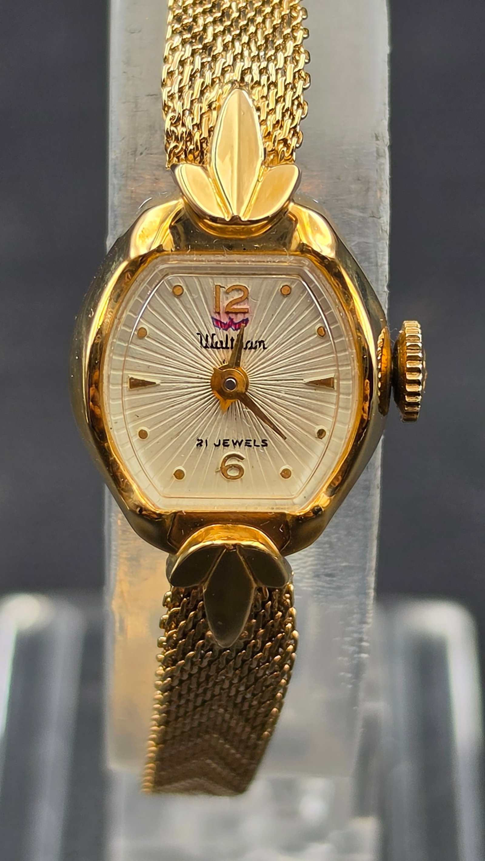 Vintage Waltham Centennial 21 Jewels Ladies Manual Wind Mesh Bracelet Watch, UTC 231, Never Worn Wit: This is a vintage Waltham ladies wristwatch with a silver sunburst-textured dial signed "Waltham" in script, with gold Arabic numerals at 12 and 6, gold dot markers at the remaining hours, and gold da