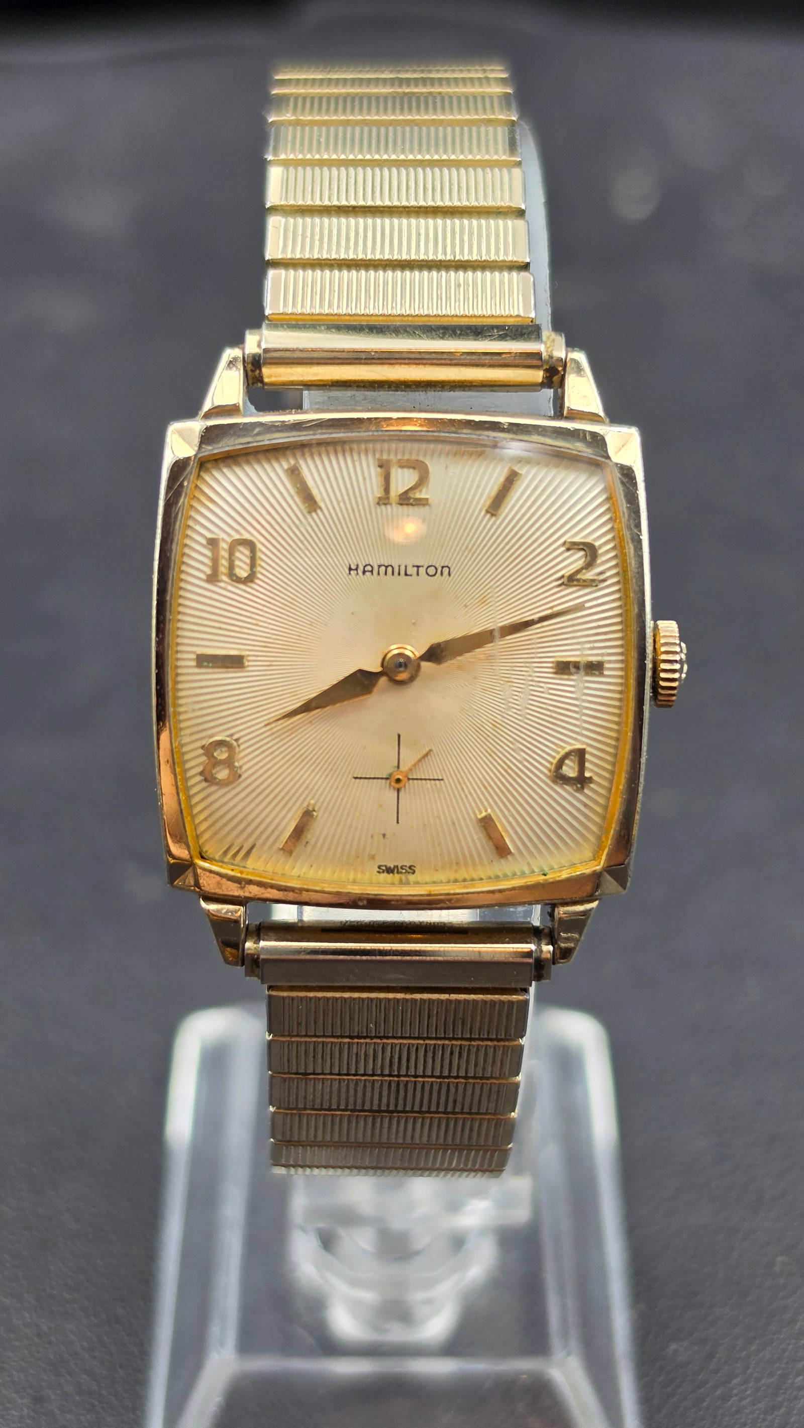 Vintage Hamilton Cal. 673 17 Jewels 10K RGP Watch With Box, Circa 1951: This is a vintage Hamilton square tank wristwatch with a sunburst-textured dial signed "Hamilton," featuring applied gold Arabic numerals at 12, 2, 4, 8, and 10, gold baton markers at the remaining ho