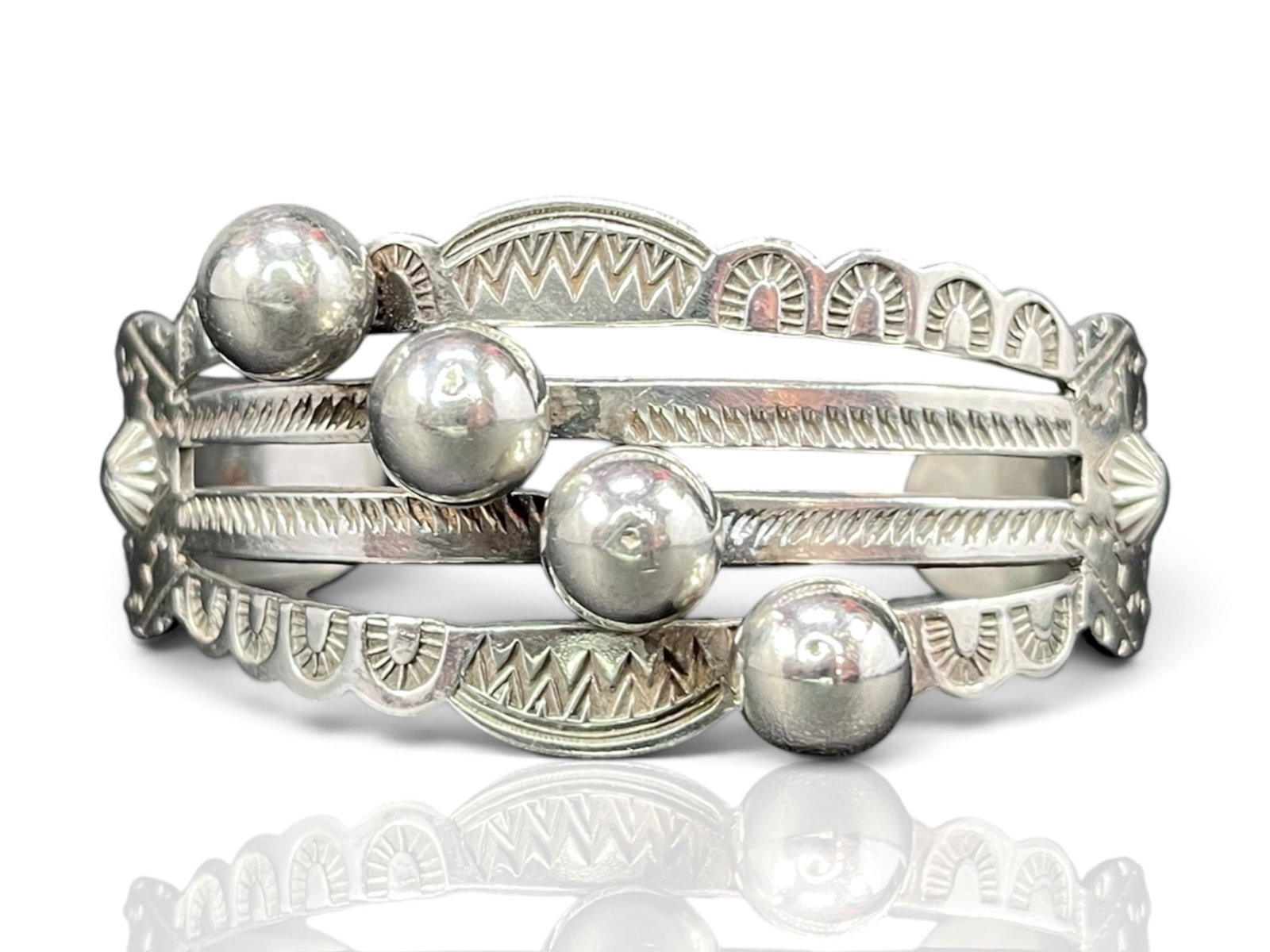 30g Navajo Sterling Silver Intricate Hand Stamped Ball Cuff: This sterling silver cuff carries the bold, hand-stamped spirit of Navajo silverwork from the American Southwest. Four ribbed bands sweep across the wrist, each rimmed with crisp chevron, arrow, and s