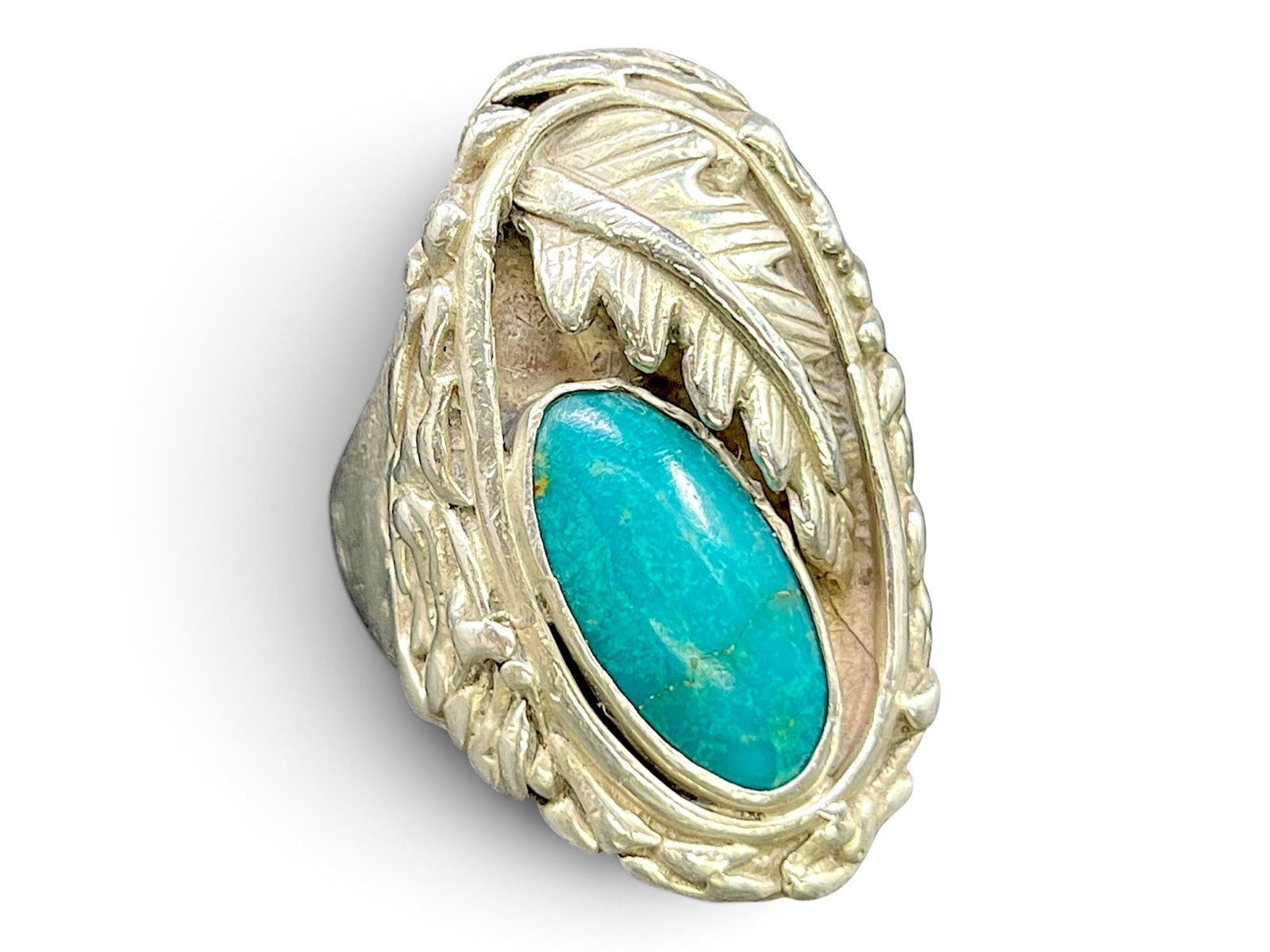 27g/Sz12 Southwestern Sterling Silver Turquoise Leaf Design Ring (Signed T): 27g/Sz12 Southwestern Sterling Silver Turquoise Leaf Design Ring (Signed T). The face centers a large oval turquoise cabochon in a blue-green tone with visible dark matrix veining running through it, 