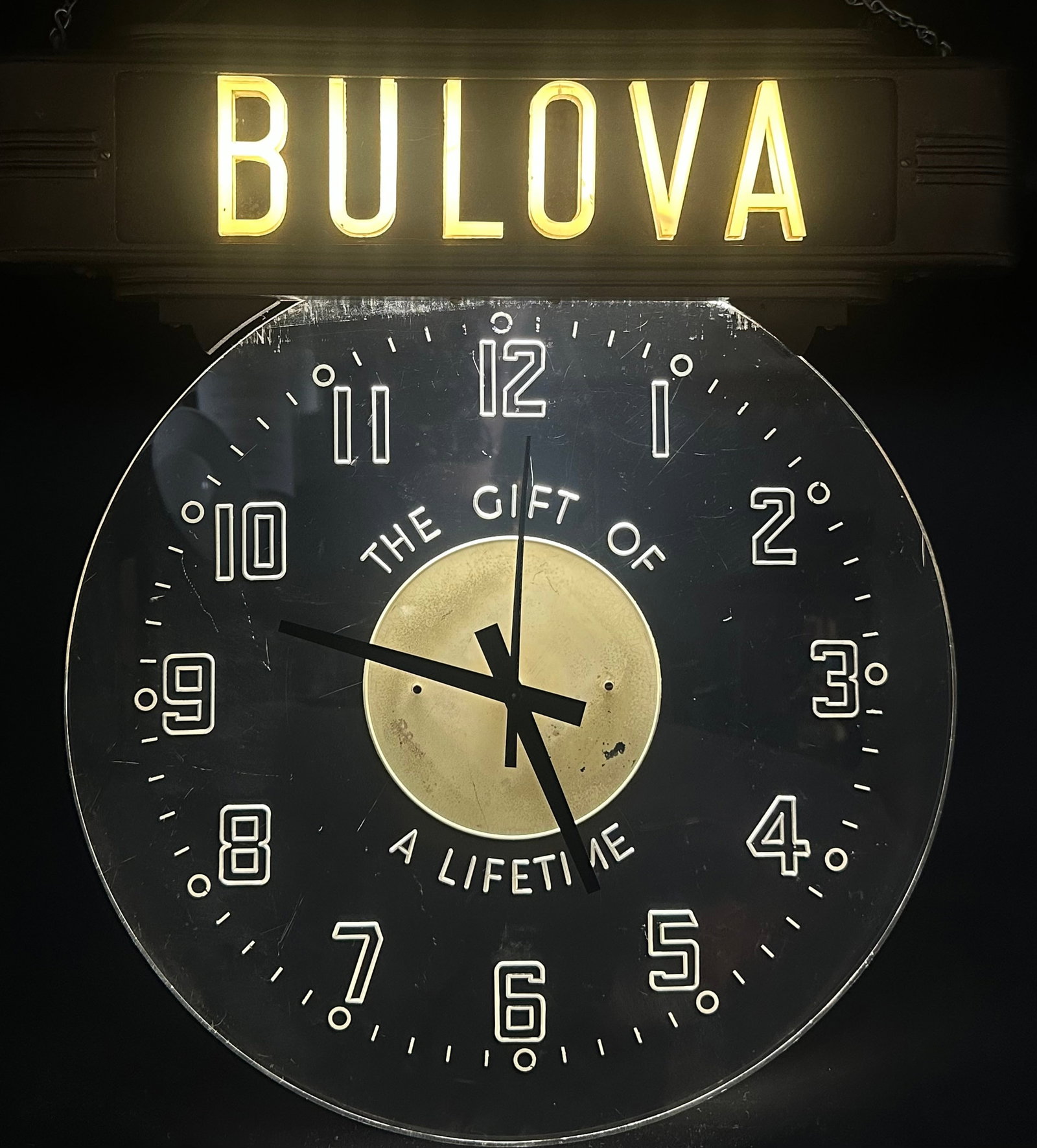 Vintage Bulova “Gift of a Lifetime” Lighted Advertising Clock: Large vintage Bulova electric jeweler’s advertising display clock featuring a clear reverse-etched dial with raised Art Deco numerals and the classic “The Gift of a Lifetime” slogan. Bronze-